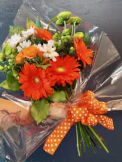Bouquet of orange gerbera daisies and white daisies with an orange polka-dot ribbon