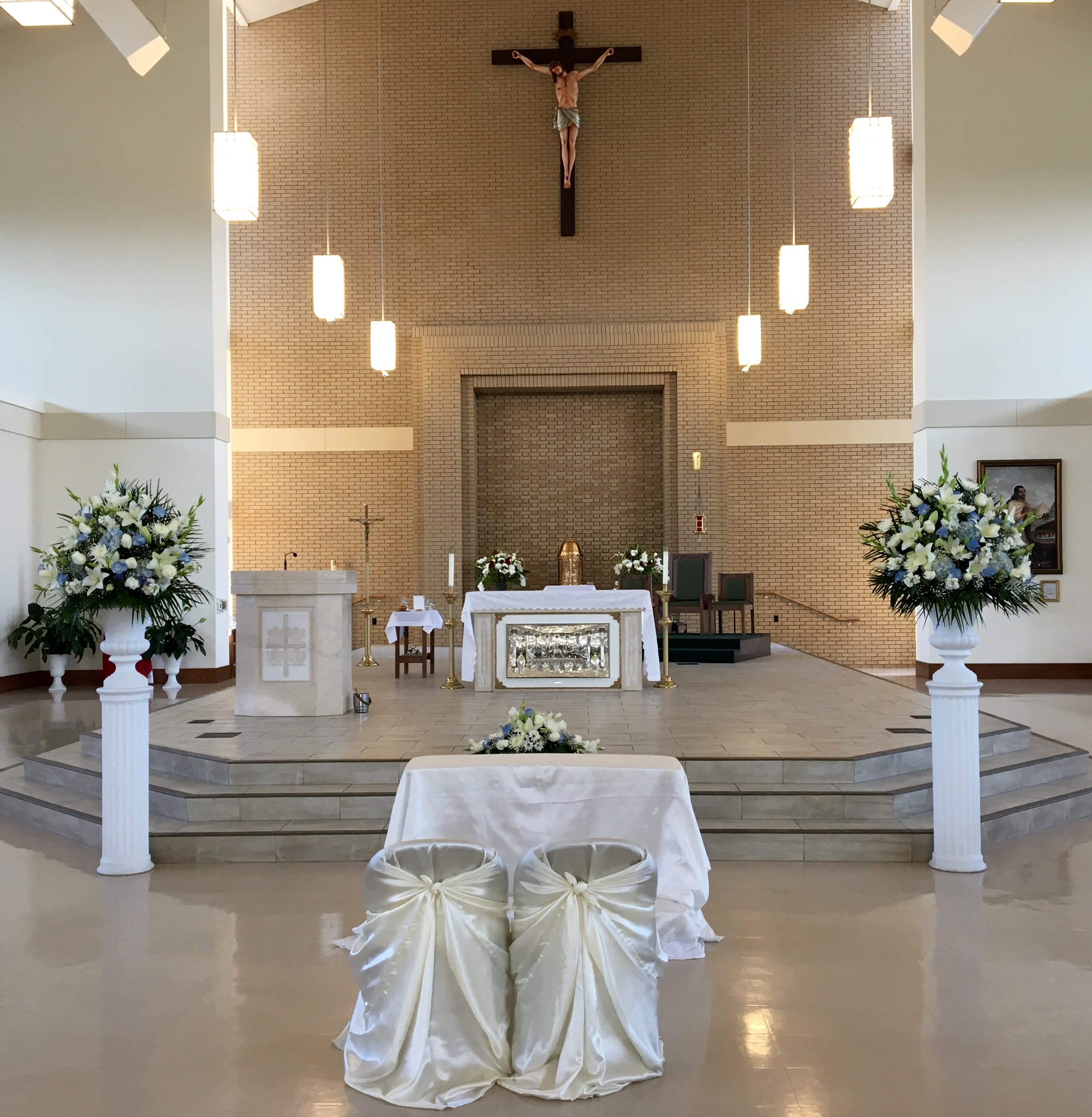 Church altar with white and blue floral arrangements on pedestals