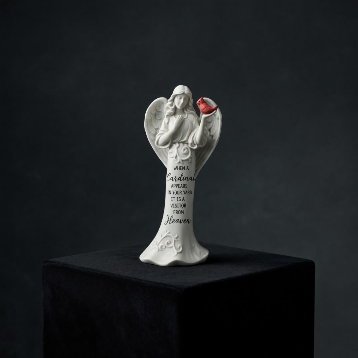 White angel figurine holding a red cardinal with memorial text