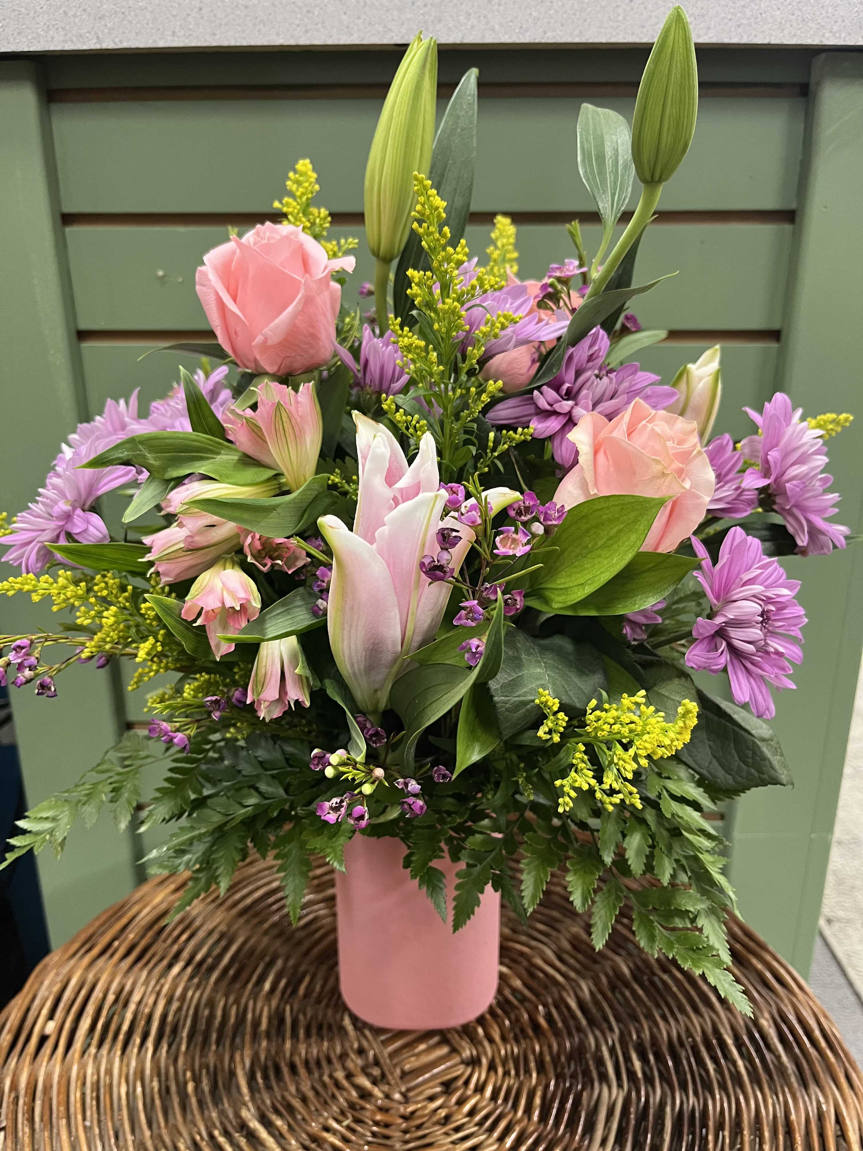 Pink roses and lilies in a pink vase with purple flowers
