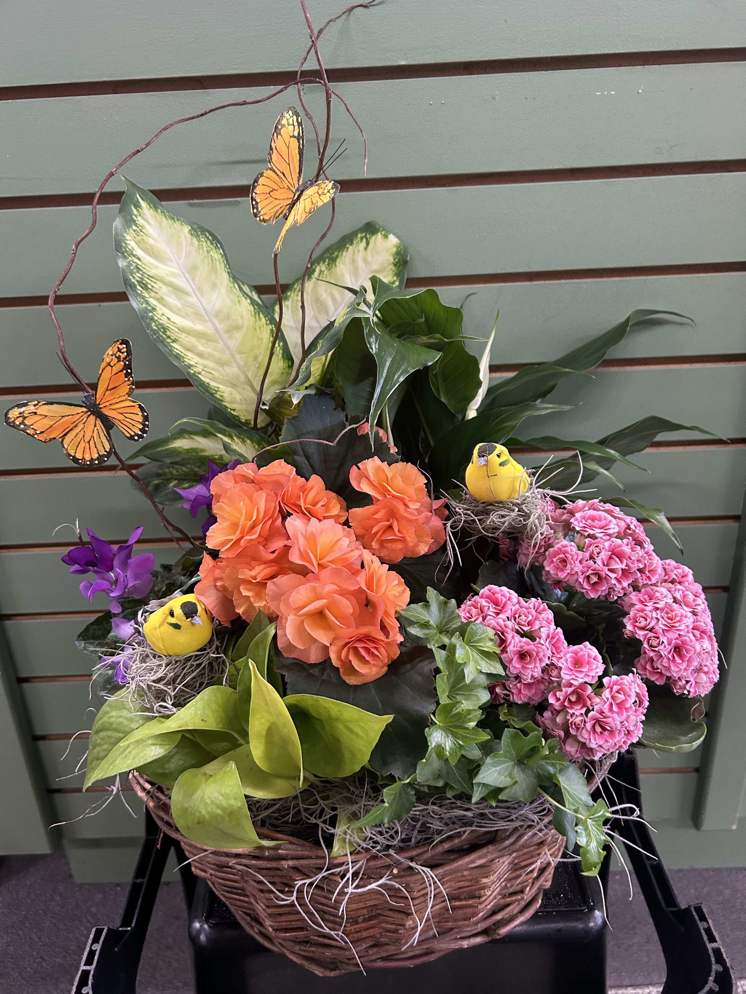 Basket arrangement with orange and pink flowers, butterflies, and small bird nests