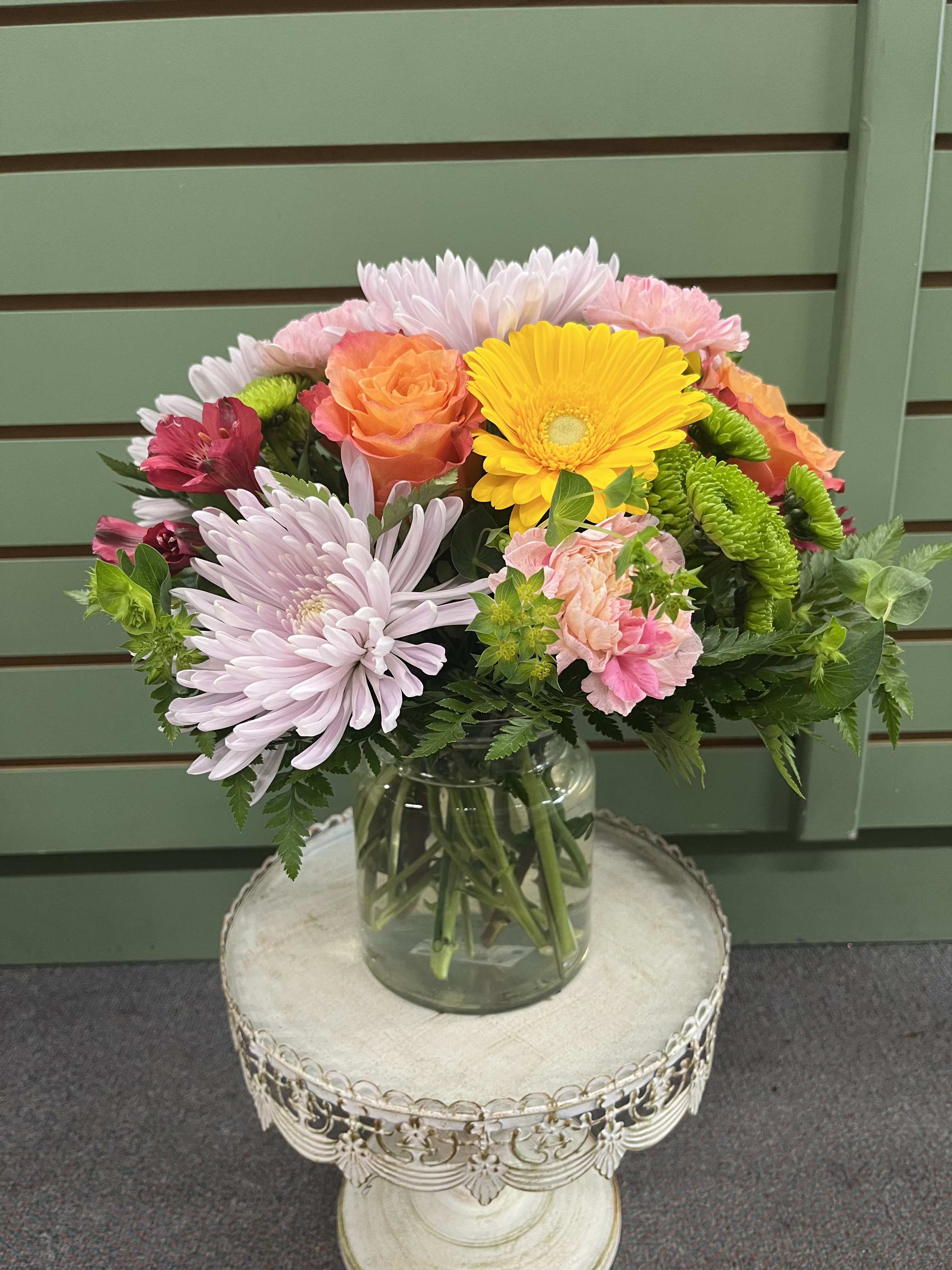Summer Sunshine - A sunny burst of bright and vibrant colors are featured in Summer Sunshine which are sure to lift anyone's spirit.   Summer Sunshine blends bright yellow gerberas, free spirit roses, two shades of pink blooms, soft lavender cremones, and green accents for a lively yet gentle look that reads summer, spring, or any cheerful celebration like a birthday bouquet, a spontaneous "just because" surprise, retirement, a thank-you, and many more.  Tightly gathered in a clear glass vase, the rounded arrangement mixes warm citrus tones with soft pinks, and lavender for an abundant, garden-fresh impression. Sized as an everyday vase arrangement, it arrives full and ready to display; simple care-fresh water and a cool spot-keeps the blooms looking bright for days.