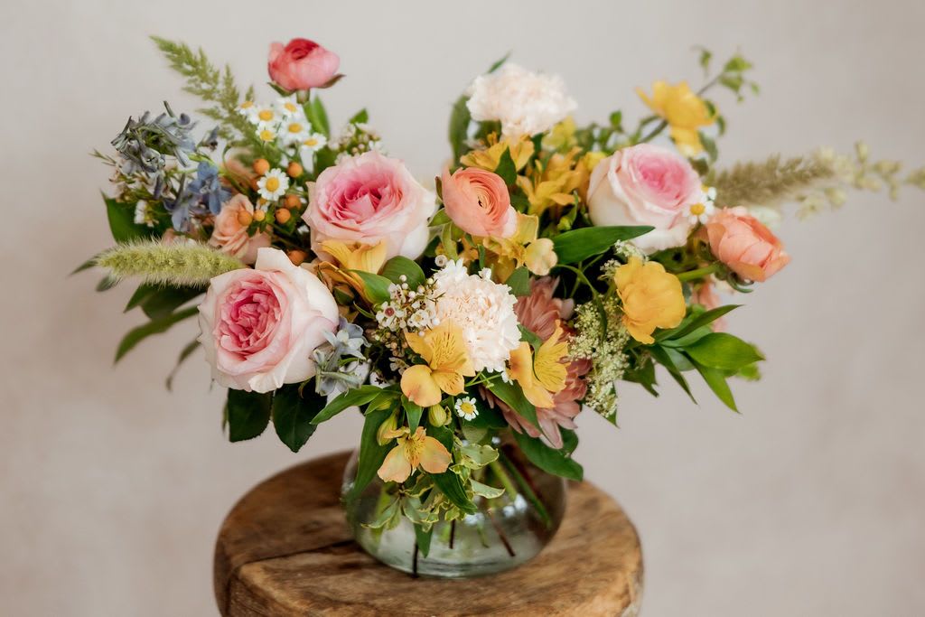 Mixed bouquet of pink and yellow flowers in a glass vase