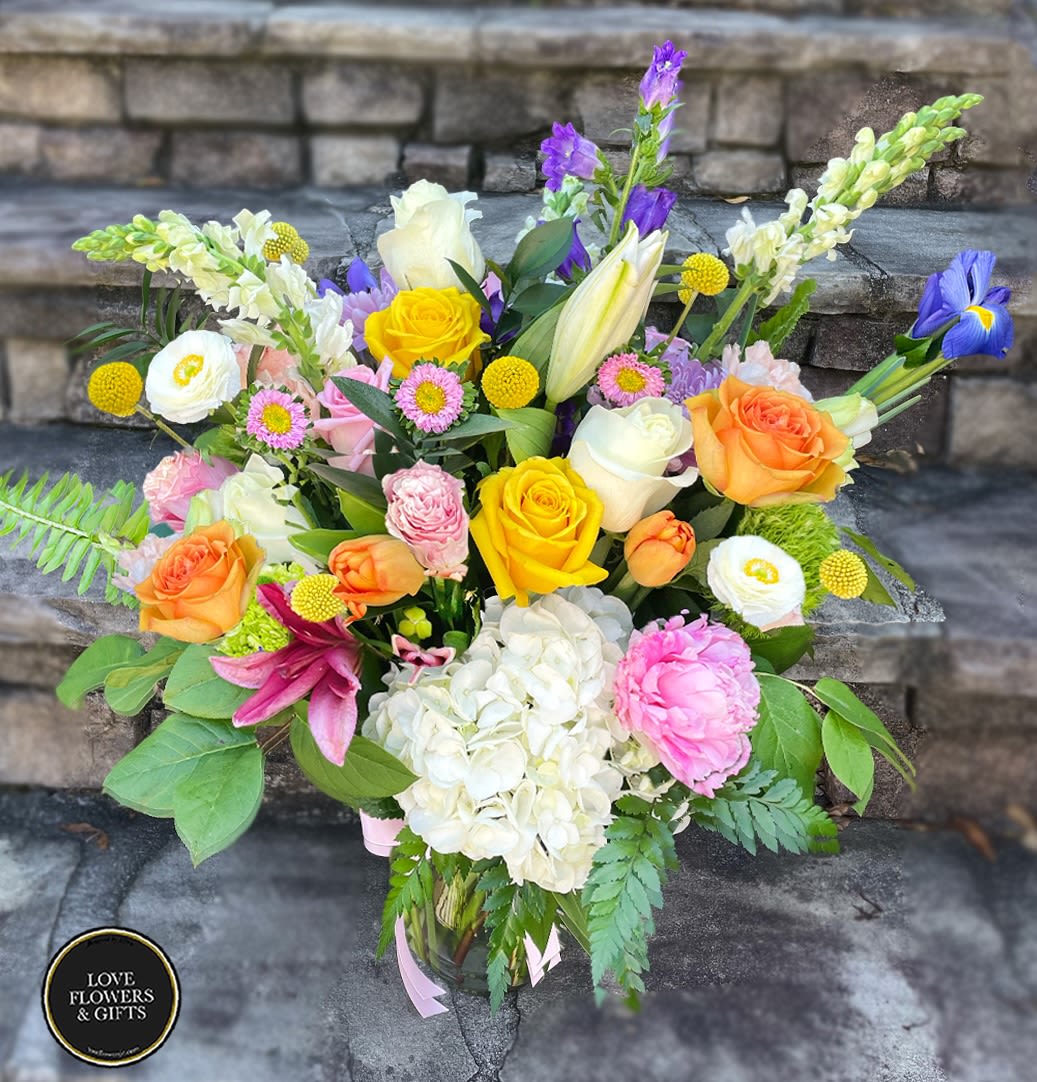 Colorful mixed bouquet of roses, lilies, hydrangea, peony and other blooms in a clear glass vase
