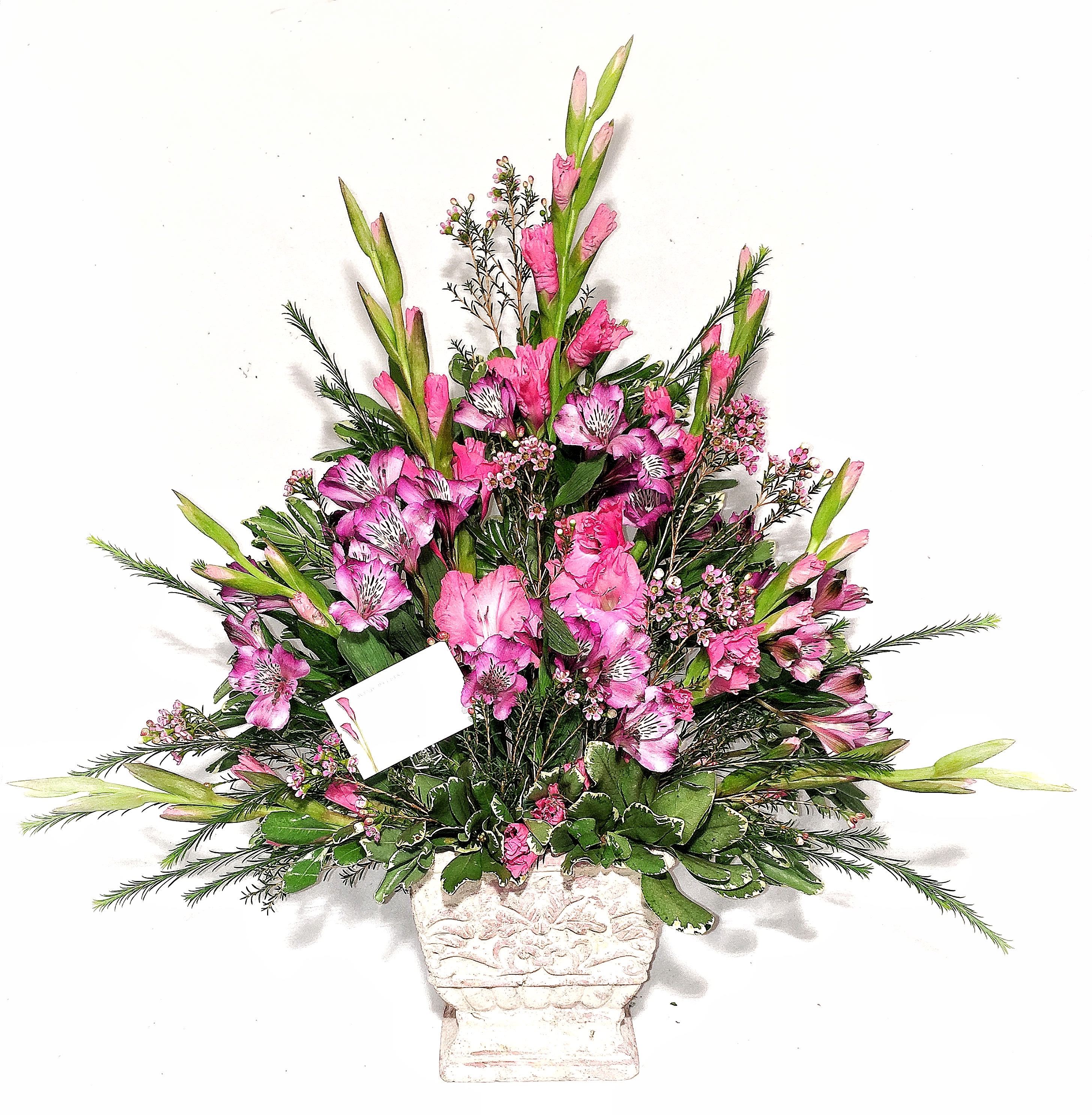 Tall pink floral arrangement in a white urn-style vase with a small card