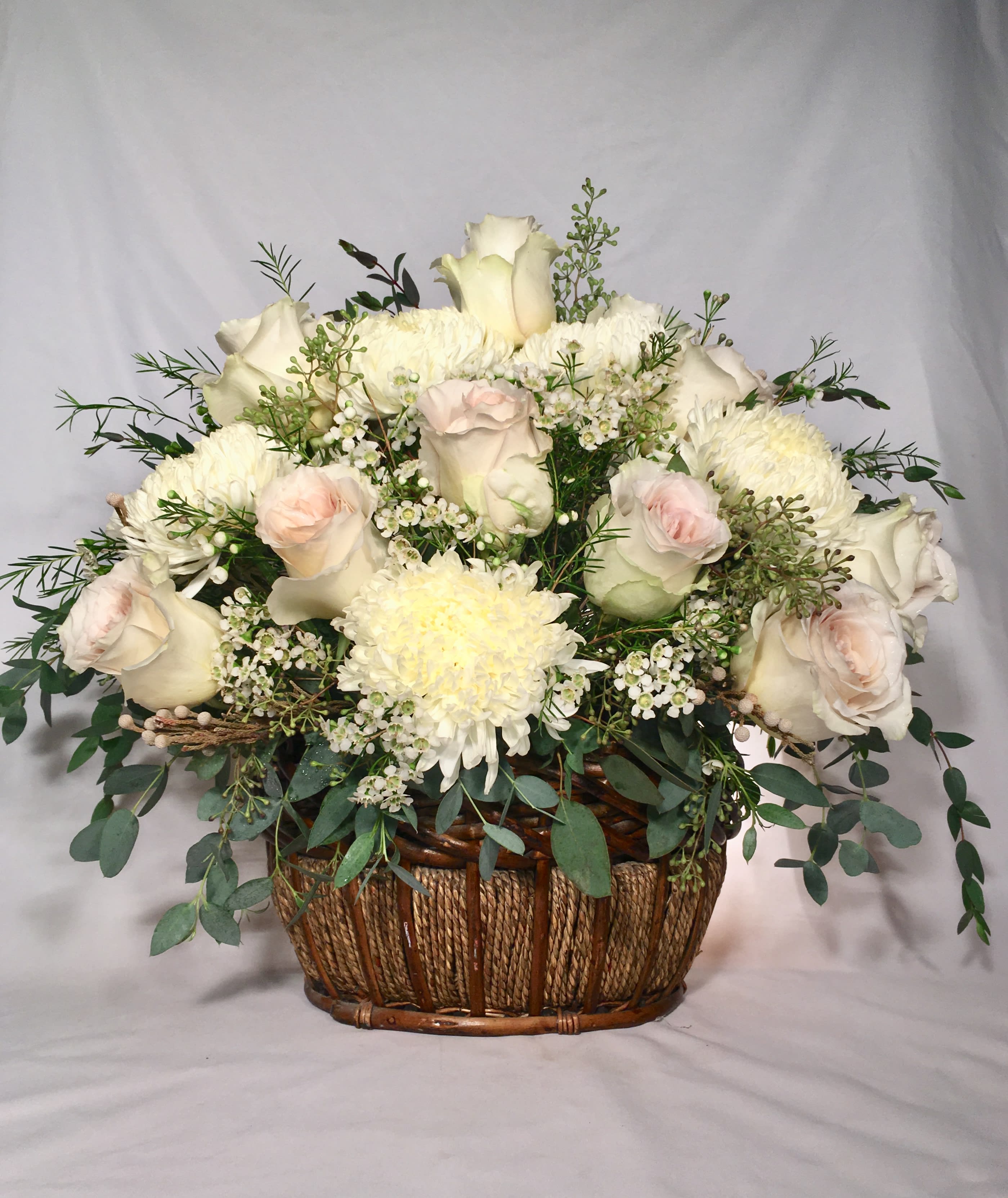 White and blush rose and mum basket arrangement with small white filler flowers
