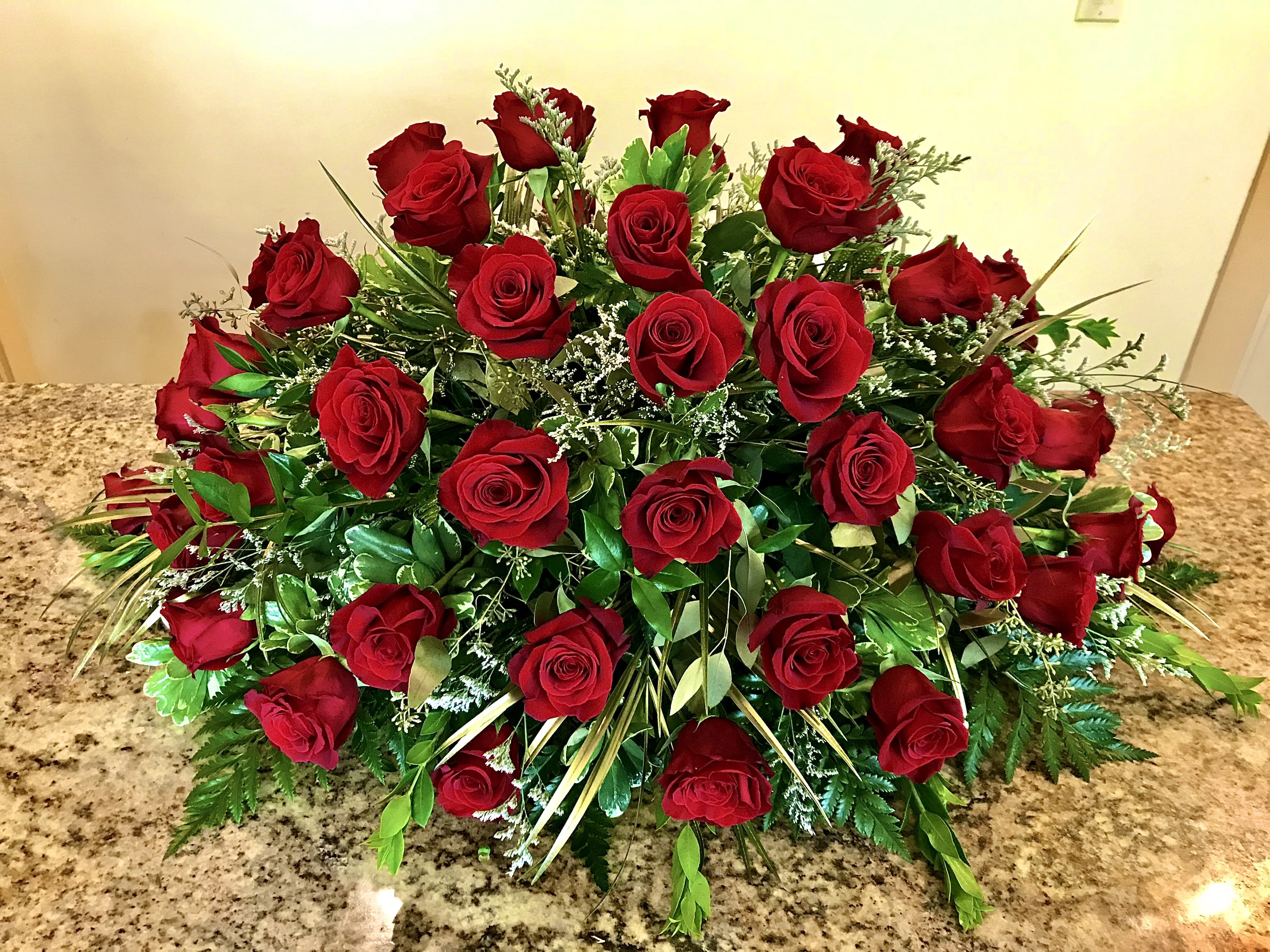 Low elongated arrangement of red roses in a dense, dome-shaped display