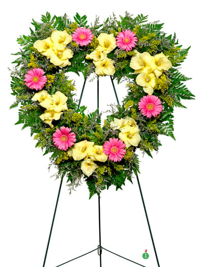 Heart-shaped green foliage wreath with yellow calla lilies and pink gerbera daisies on a metal stand