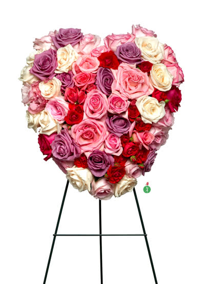 Heart-shaped standing arrangement of pink, red, and lavender roses on a metal easel