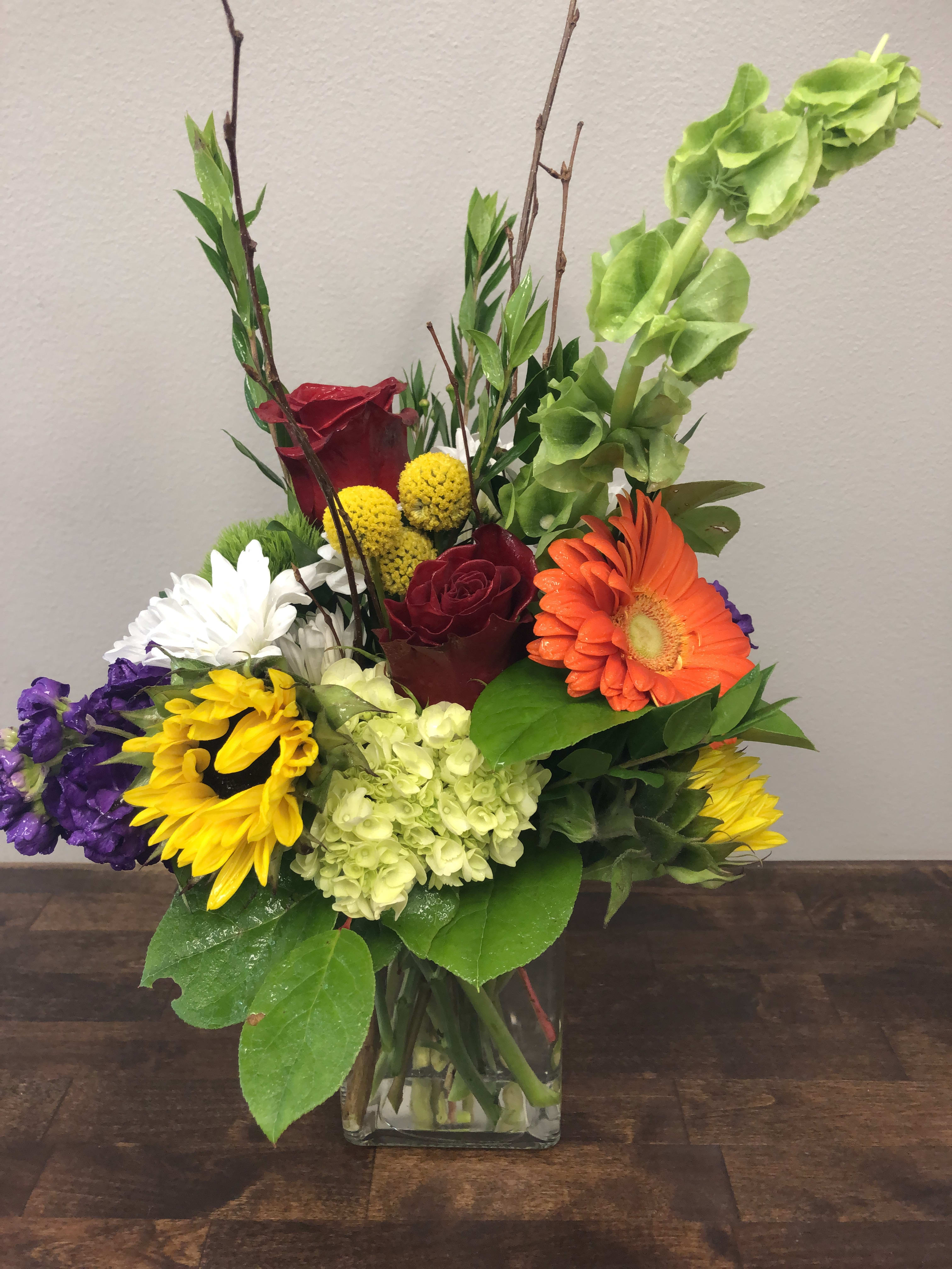 Garden Walk - A walk through the garden, fresh bright colors in yellows, reds, oranges and other colors to balance the boldness of this design.  We custom create each arrangement at the time of order.  The design will have the look and feel of the shown pictures, but flower variety and vase will likely be slightly different.