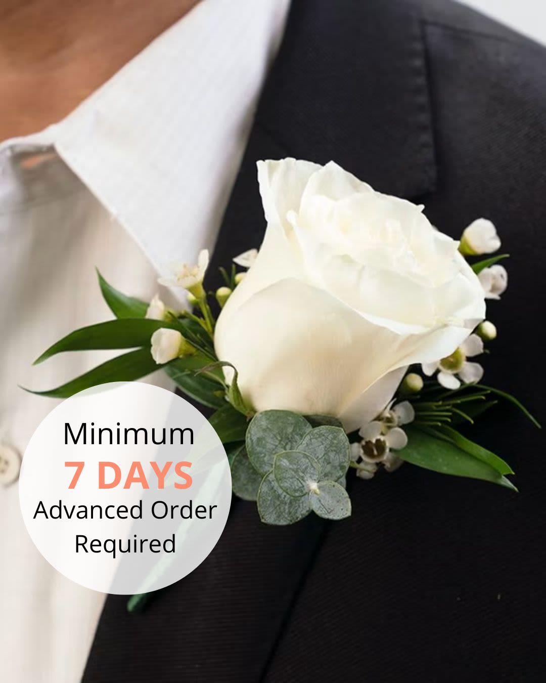 White rose boutonniere pinned to a black suit jacket lapel