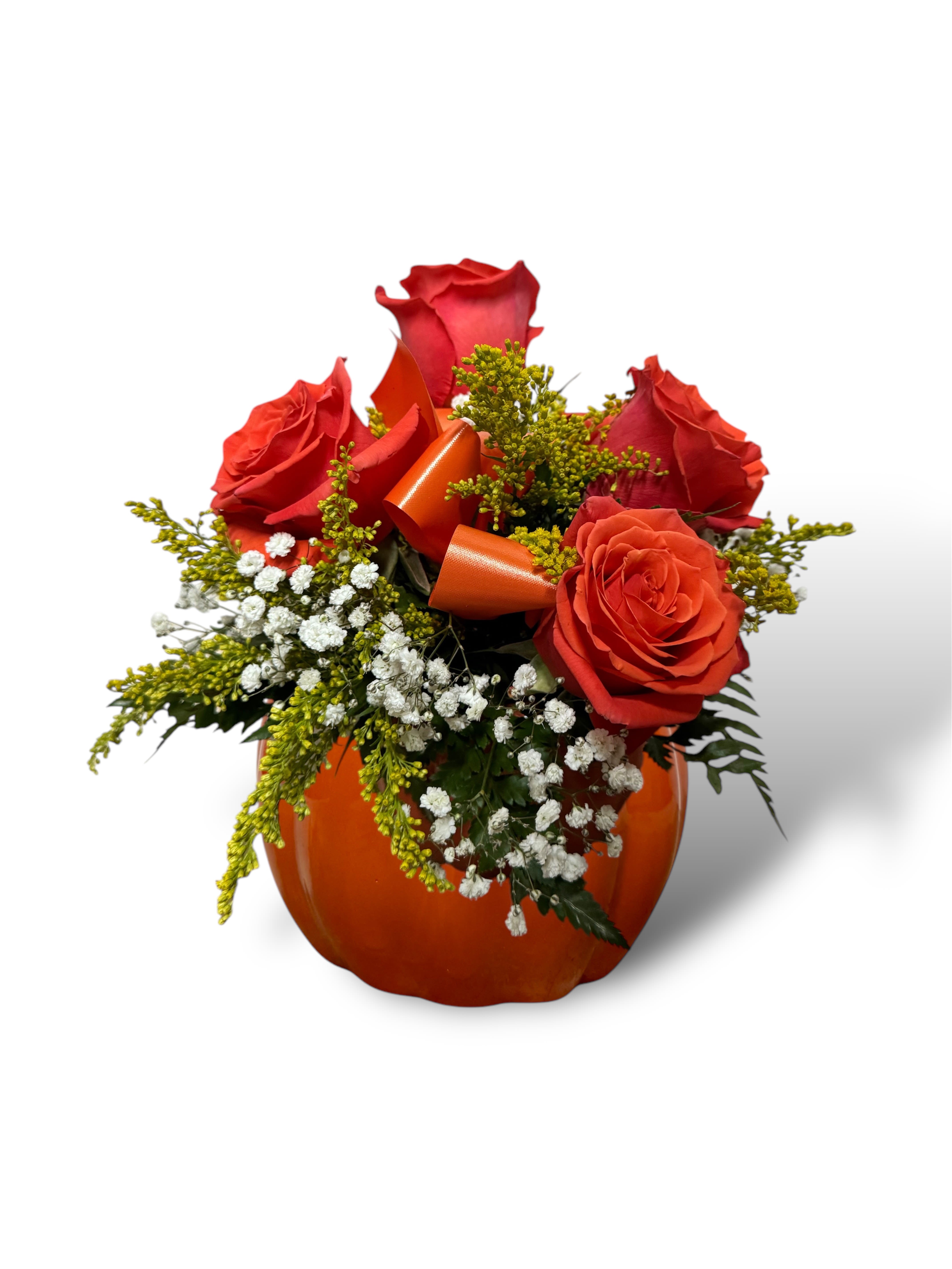 Red roses arranged in an orange pumpkin-shaped container with ribbon