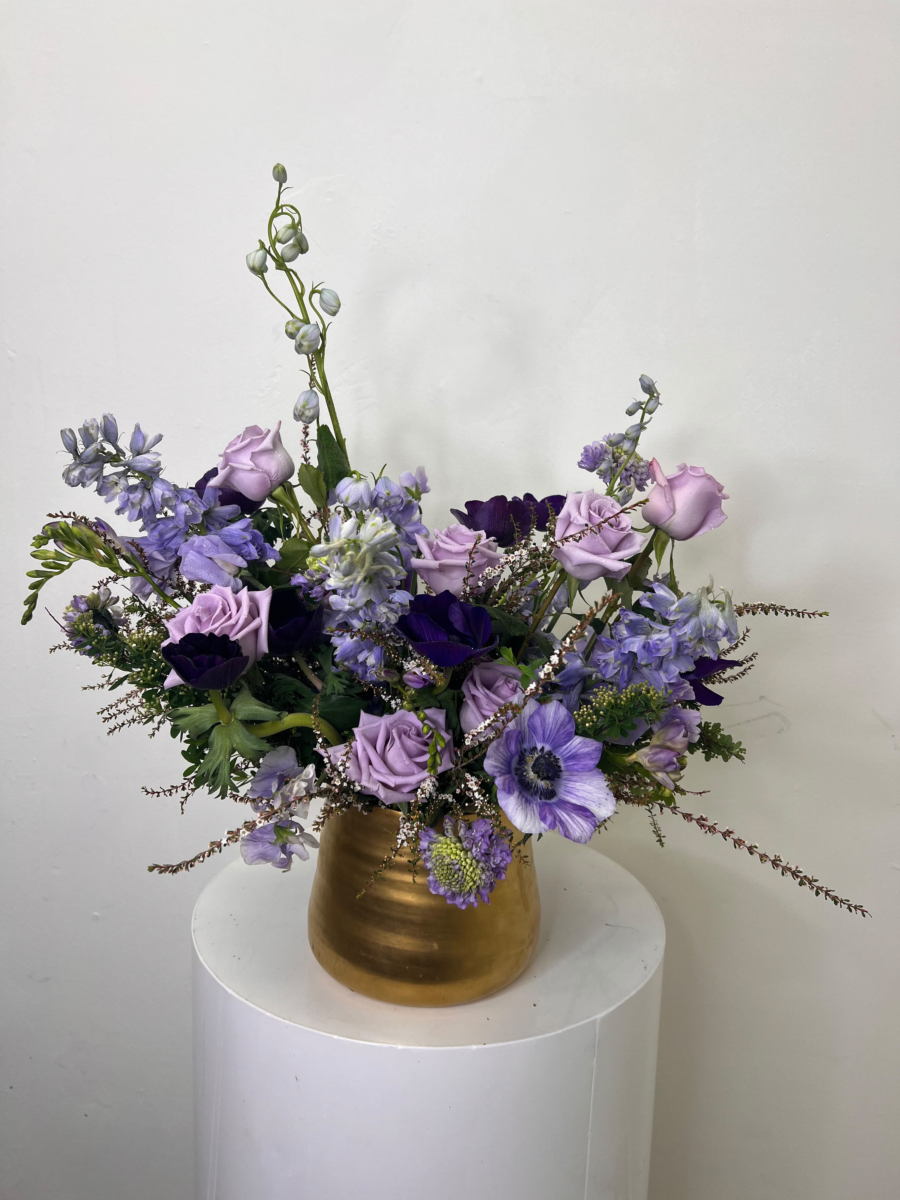 Purple Haze - Lavender roses and deep purple anemones combine in a garden-style bouquet that reads like a twilight spring meadow - perfect as a birthday bouquet, anniversary flowers, or just because for someone who loves feminine, romantic color. The Purple Haze arrangement uses airy delphinium-like spikes and tall snapdragon stems to create a slightly dramatic, outward-spreading silhouette that looks effortless and elegant in the moment they receive it.