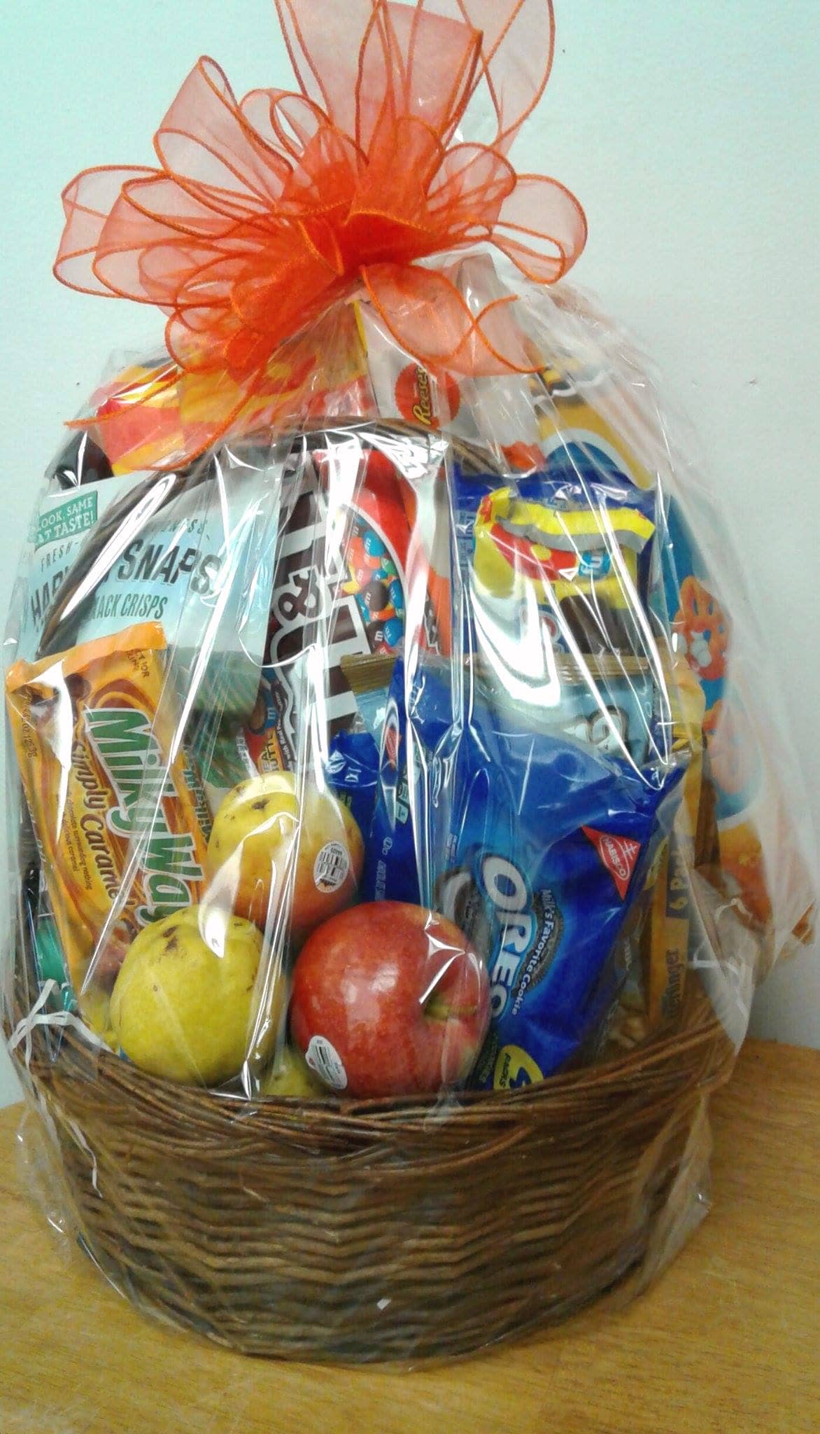 Gift basket of assorted snacks and fruit in a wicker basket