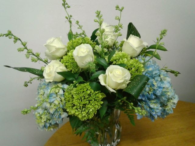 White roses and blue hydrangeas in a clear glass vase