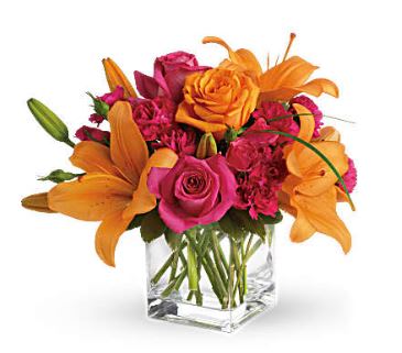 Orange lilies and pink roses arranged in a clear glass vase