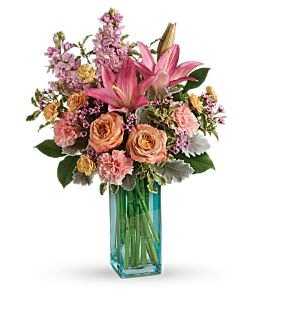 Pink and peach floral arrangement in a blue glass vase