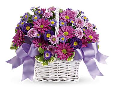 Purple and pink daisy bouquet in a white basket with lavender ribbon