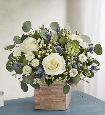 Country Pearl Arrangement  - This charming, country-inspired bouquet delivers joy with soothing, pearl-white blooms in a loose, natural style and a fresh succulent for an extra eye-catching touch. We've placed creamy white roses and button poms, delicate limonium, white hypericum and blue thistle and accented them beautifully with a living succulent plant and assorted greenery, all in a grey-washed wooden cube, with soft tones and natural textures that add warmth to any décor!  Available for same-day delivery to Washington Park, Platt Park and most neighborhood locations by your favorite florist, Floral Expressions!   