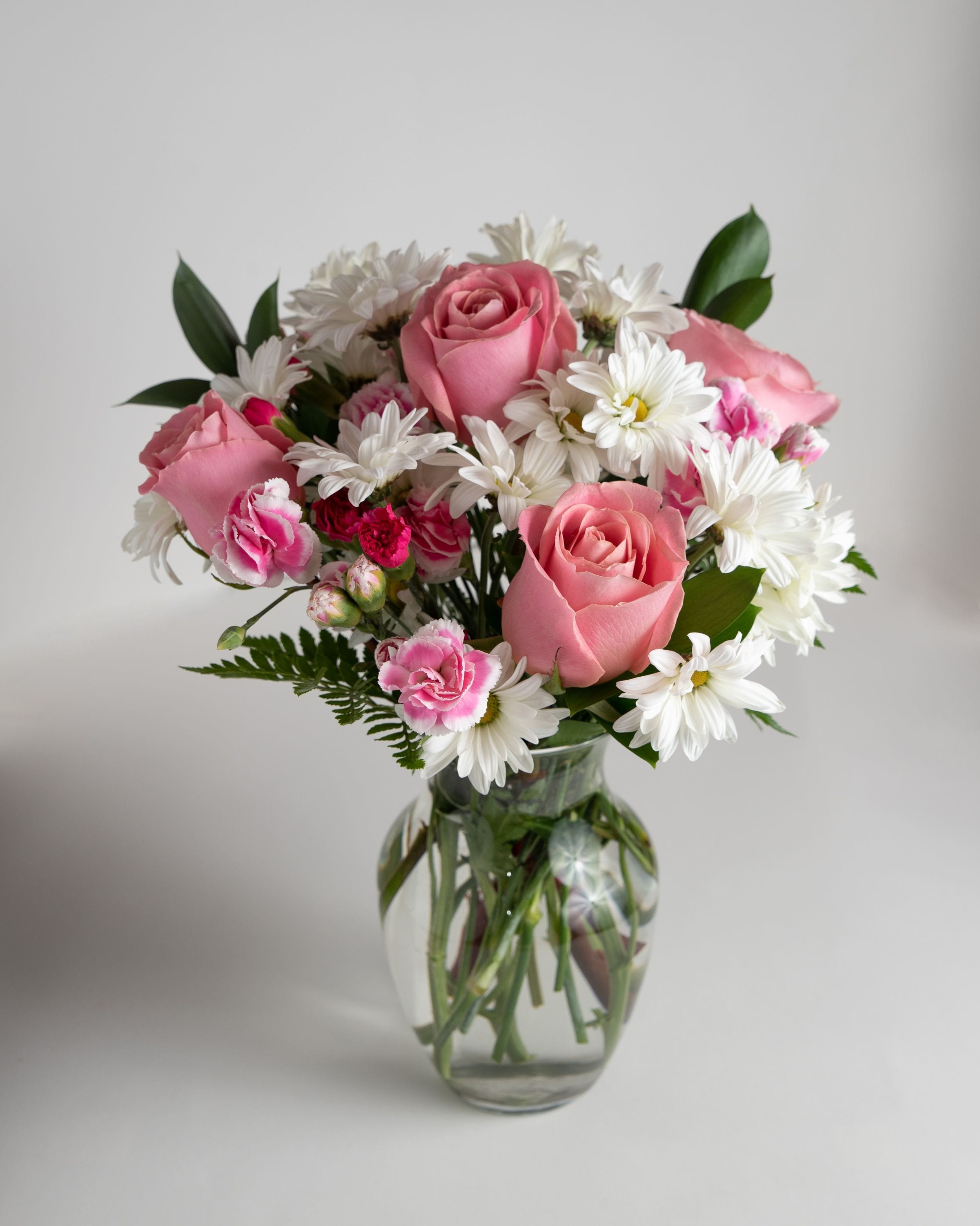 Surprisingly Sweet - A soft collection of white Daisies, 2 tones of pink mini Carnations and pink Roses. Sweeten up anyone's day with this fan favorite.