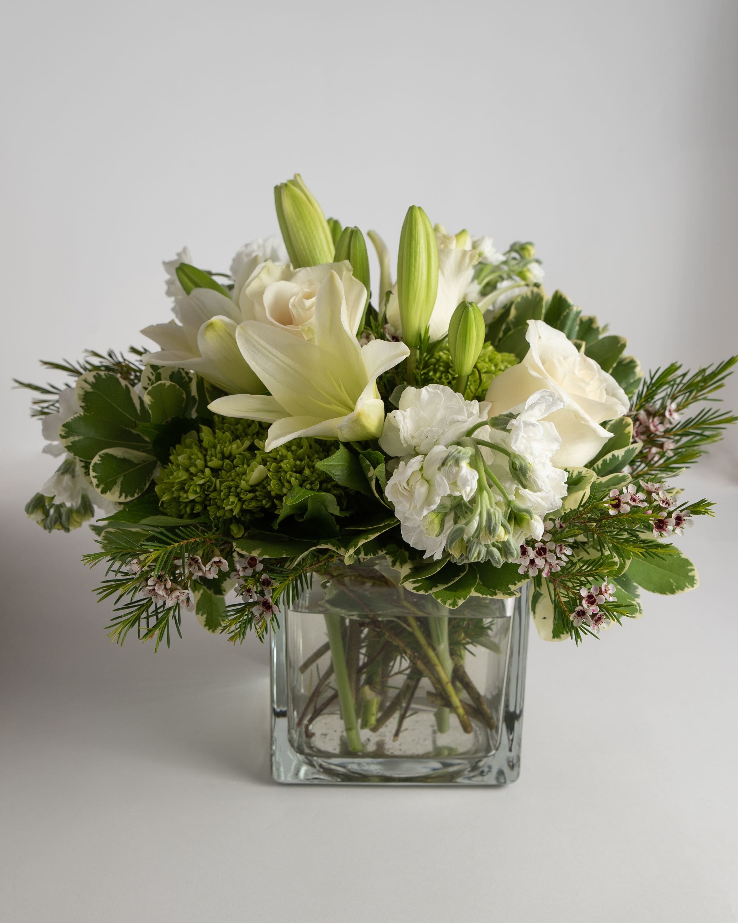 White lilies and roses arranged in a clear glass vase