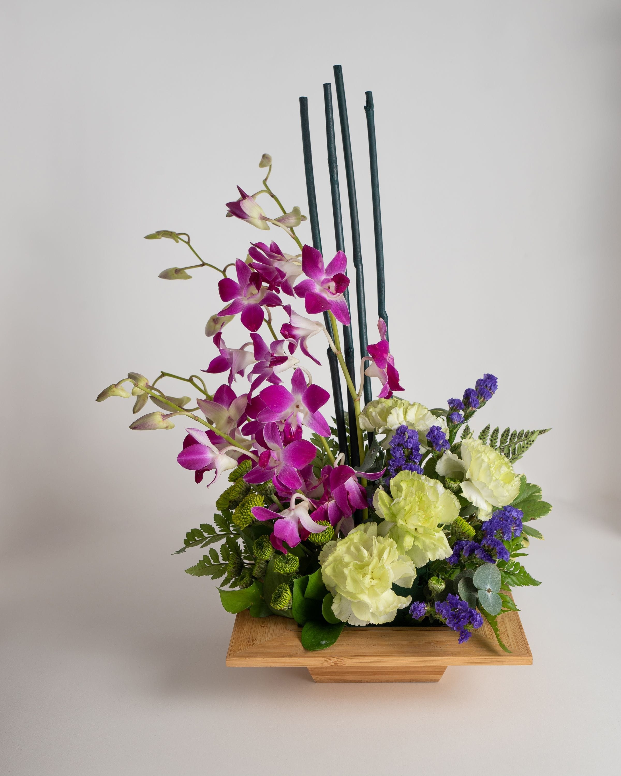 Purple orchids and pale carnations in a wooden container