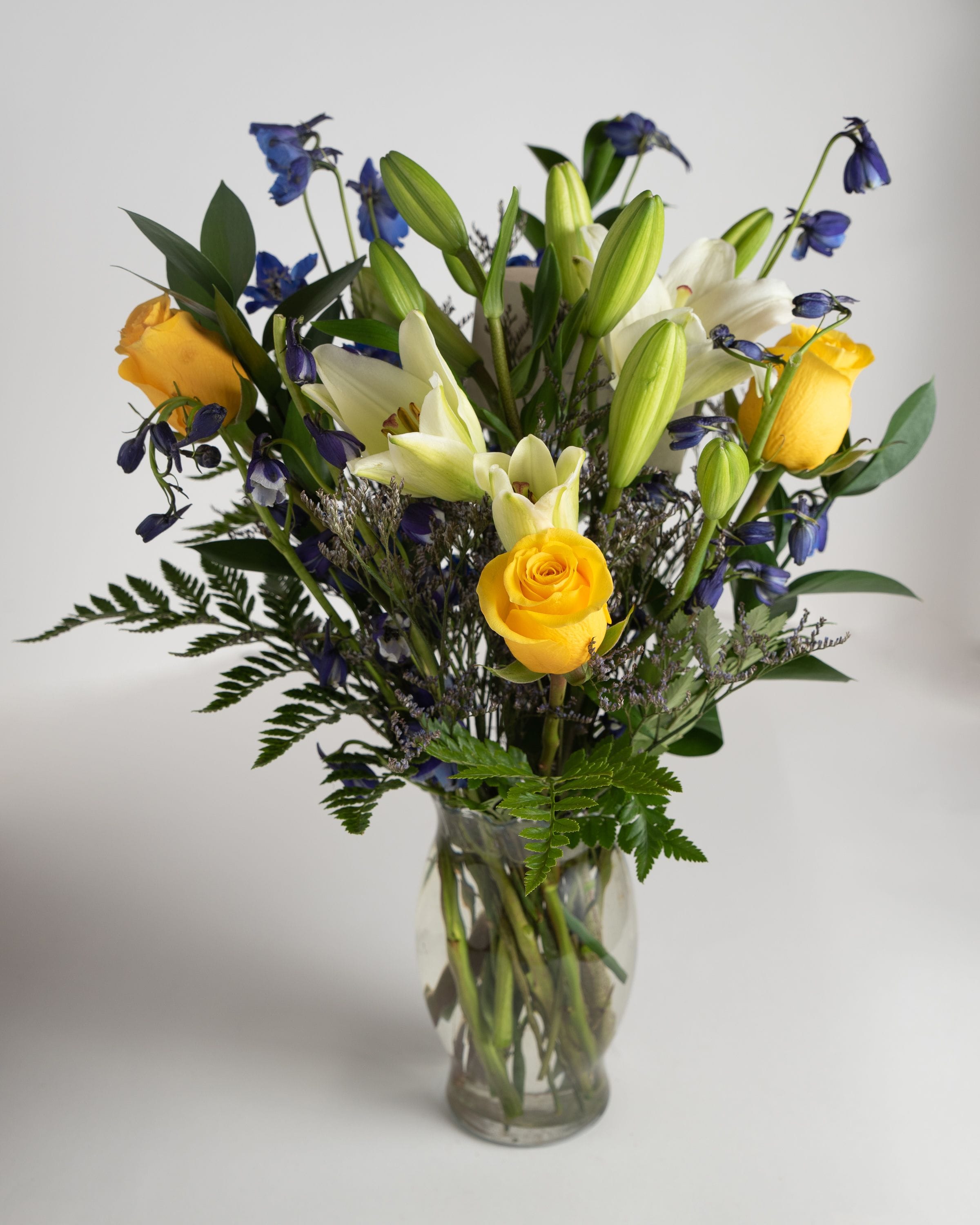 Yellow roses and white lilies in a clear glass vase