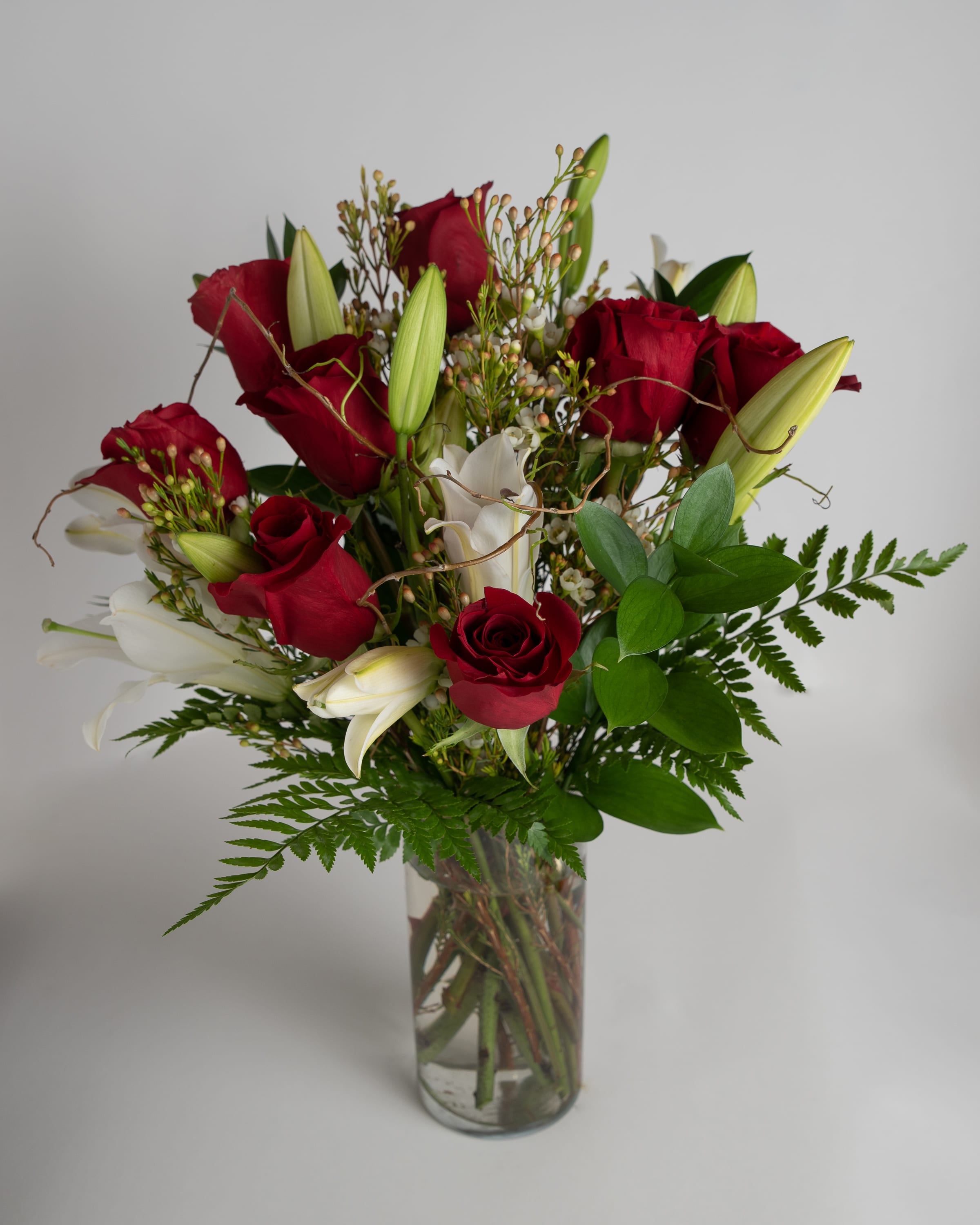 Red roses and white lilies arranged in a clear glass vase
