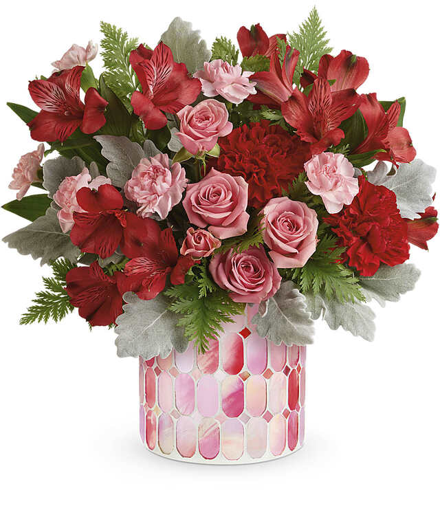 Pink and red flower arrangement in a patterned vase