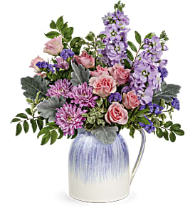 Mixed pink and purple flowers in a blue-and-white ceramic pitcher