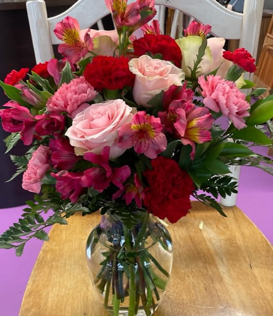 Mixed bouquet of pink and red flowers in a clear glass vase