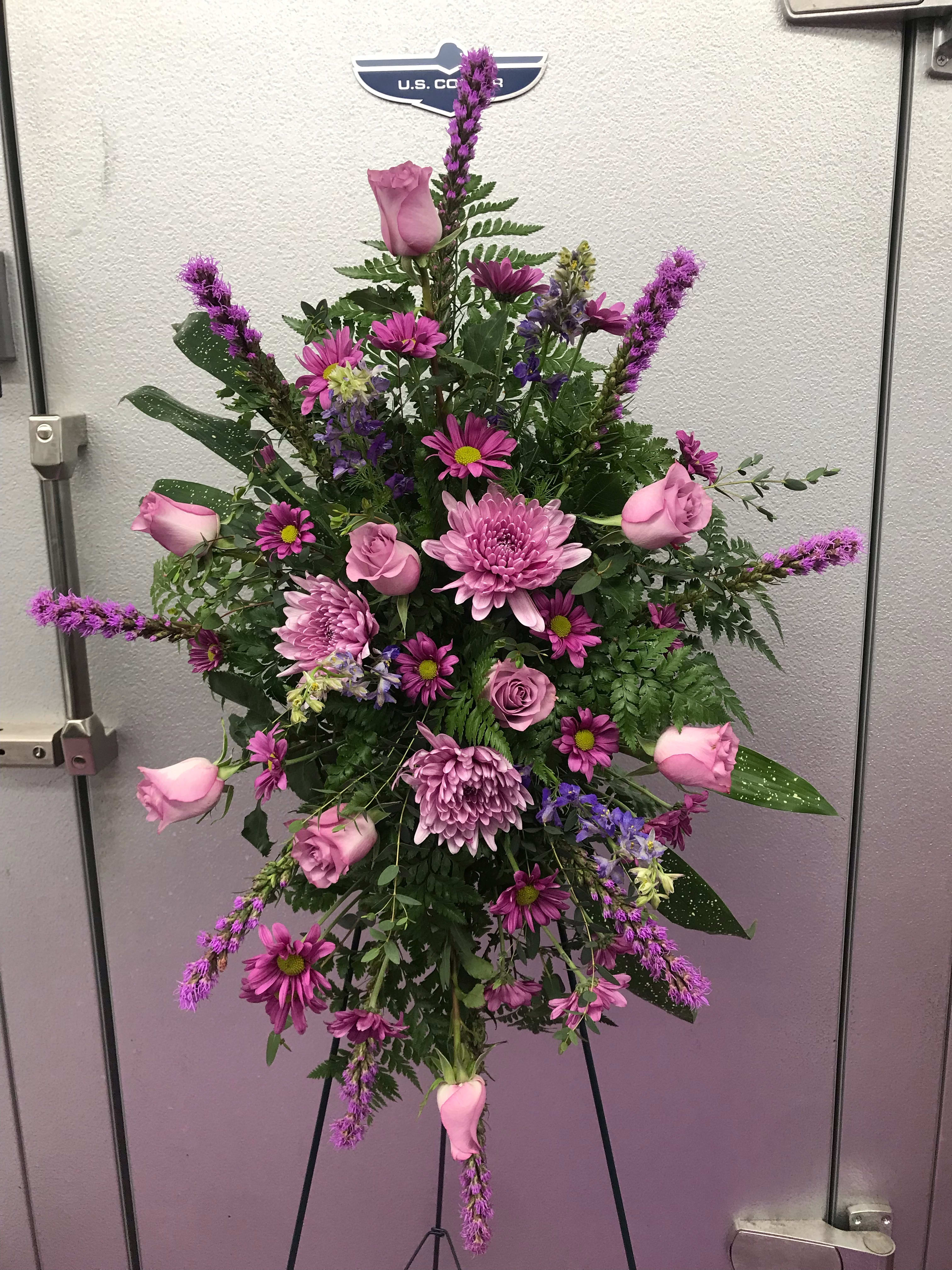 Lovingly Lavender Standing Spray - A collection of lavender and purple flowers arranged on a tall, standing easel.