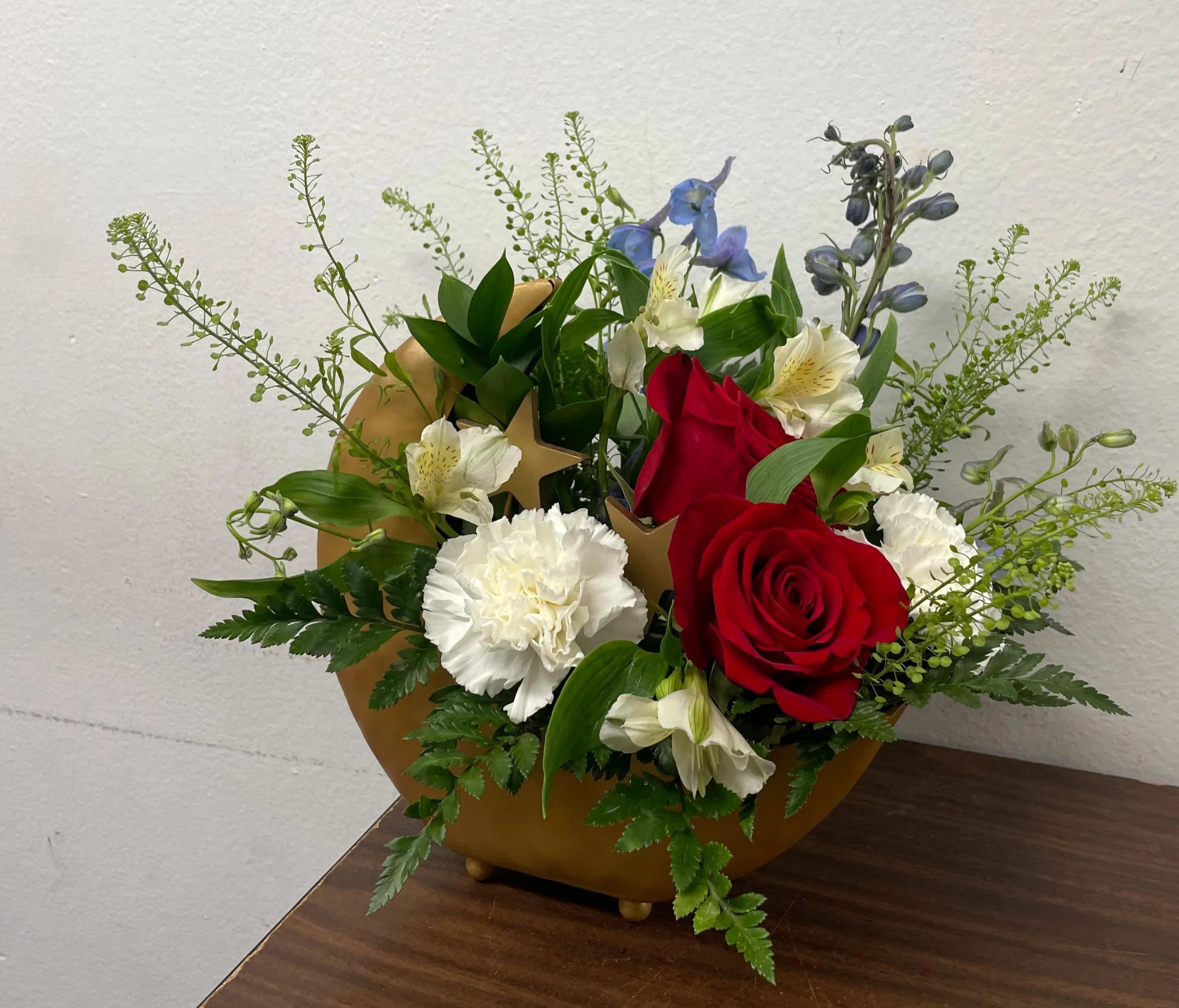 Red roses and white carnations in a gold vase with blue accents