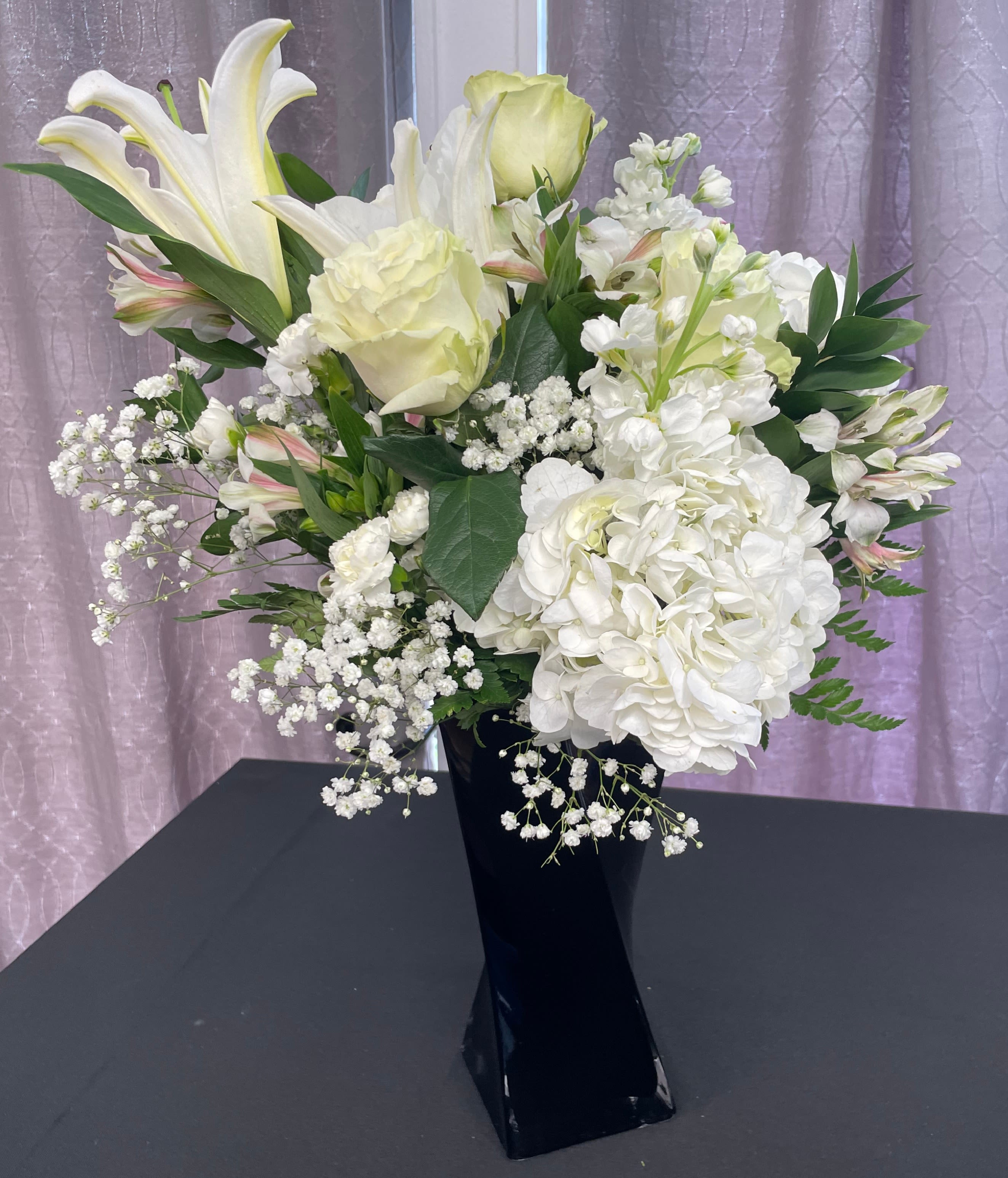 White lilies and hydrangeas in a black vase