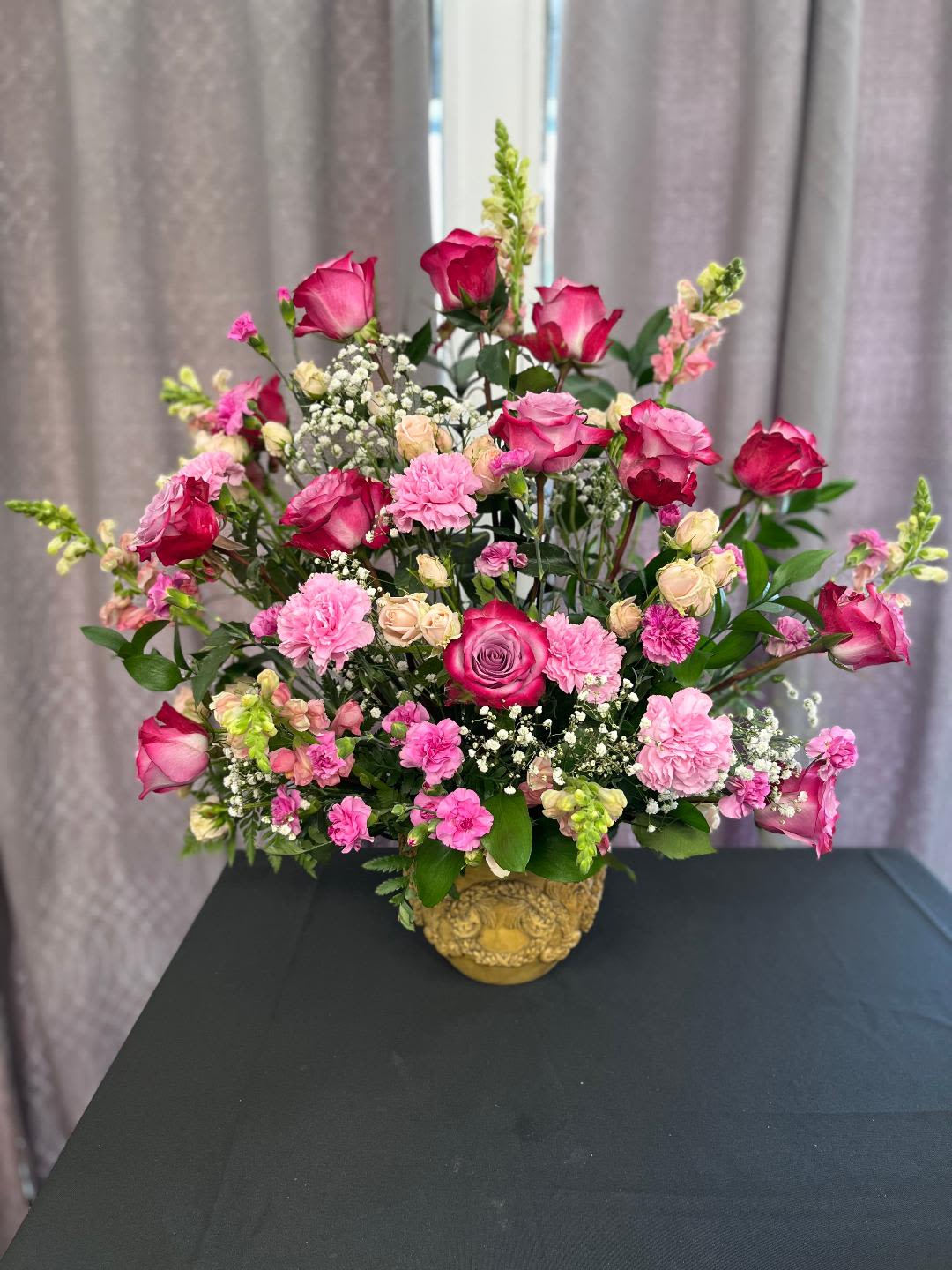 Pink roses and carnations arranged in a gold vase
