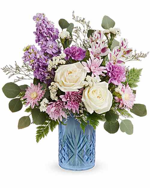 Purple and white mixed bouquet in a blue glass vase