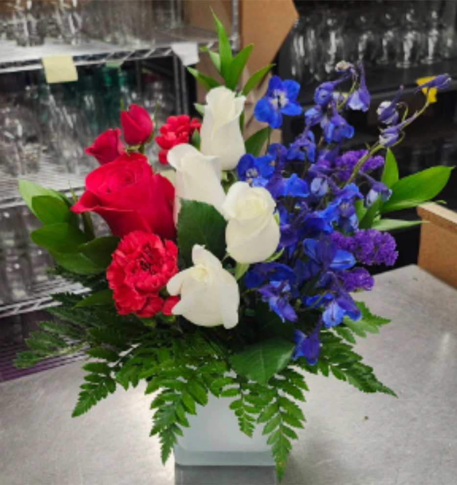 Red, White and Bloom - A blend of Red roses, white roses, blue delphinium and greens.