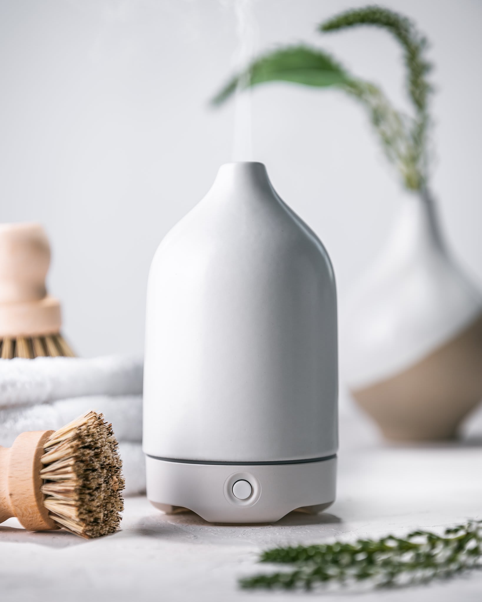 White ceramic essential oil diffuser emitting mist on a spa-like counter