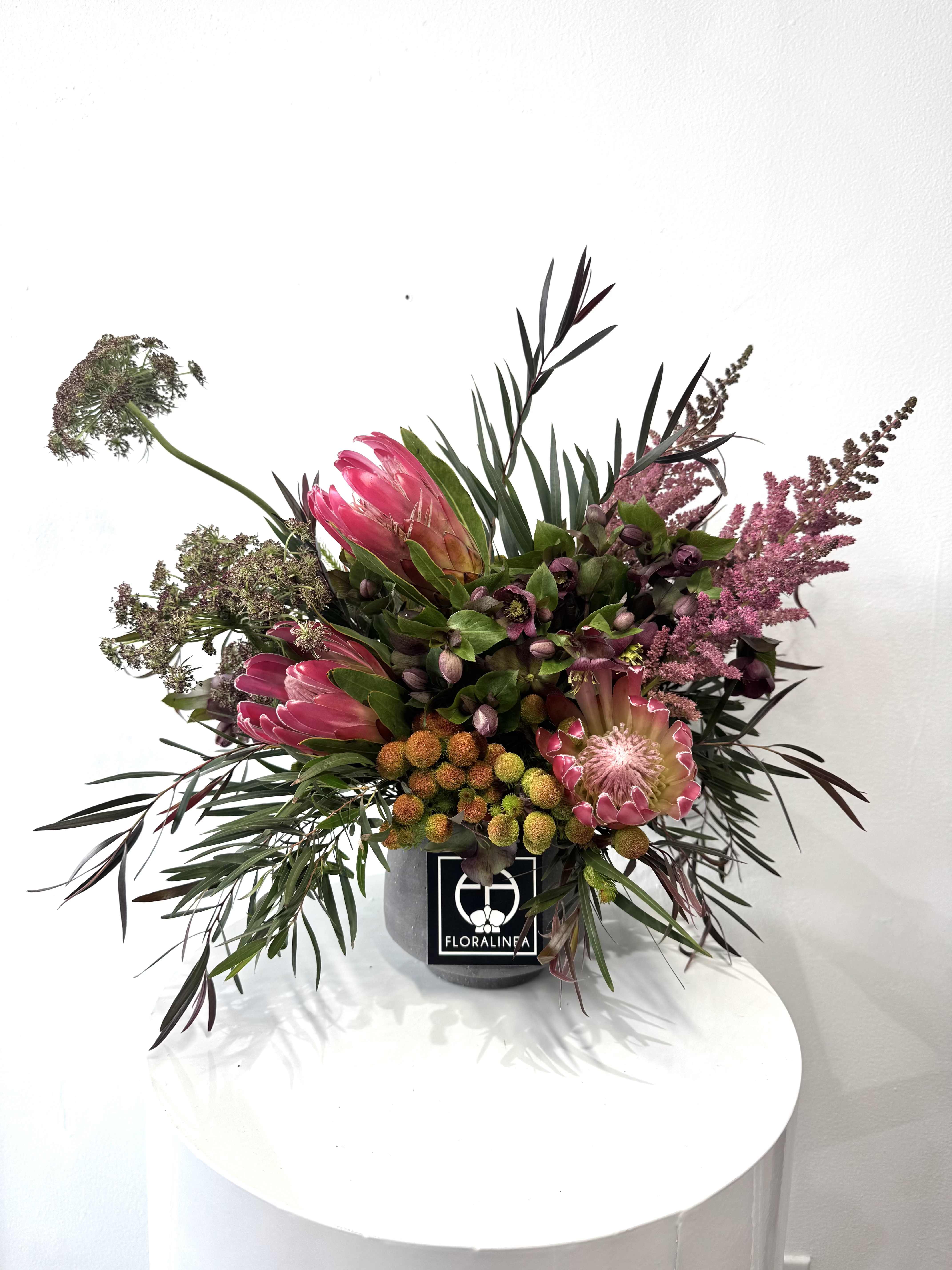 Pink protea arrangement in a gray container