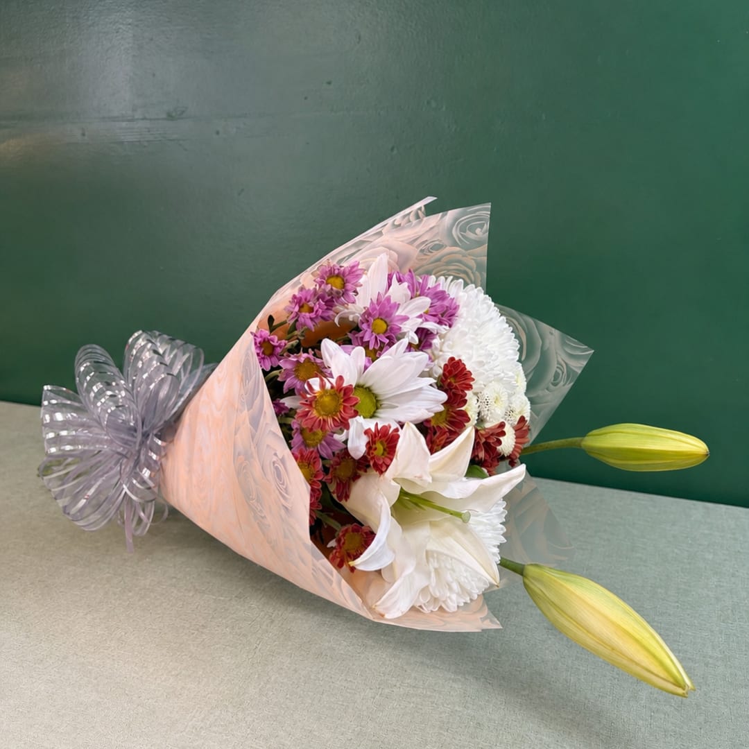 Bouquet of white lilies and mixed daisy flowers wrapped in pink paper