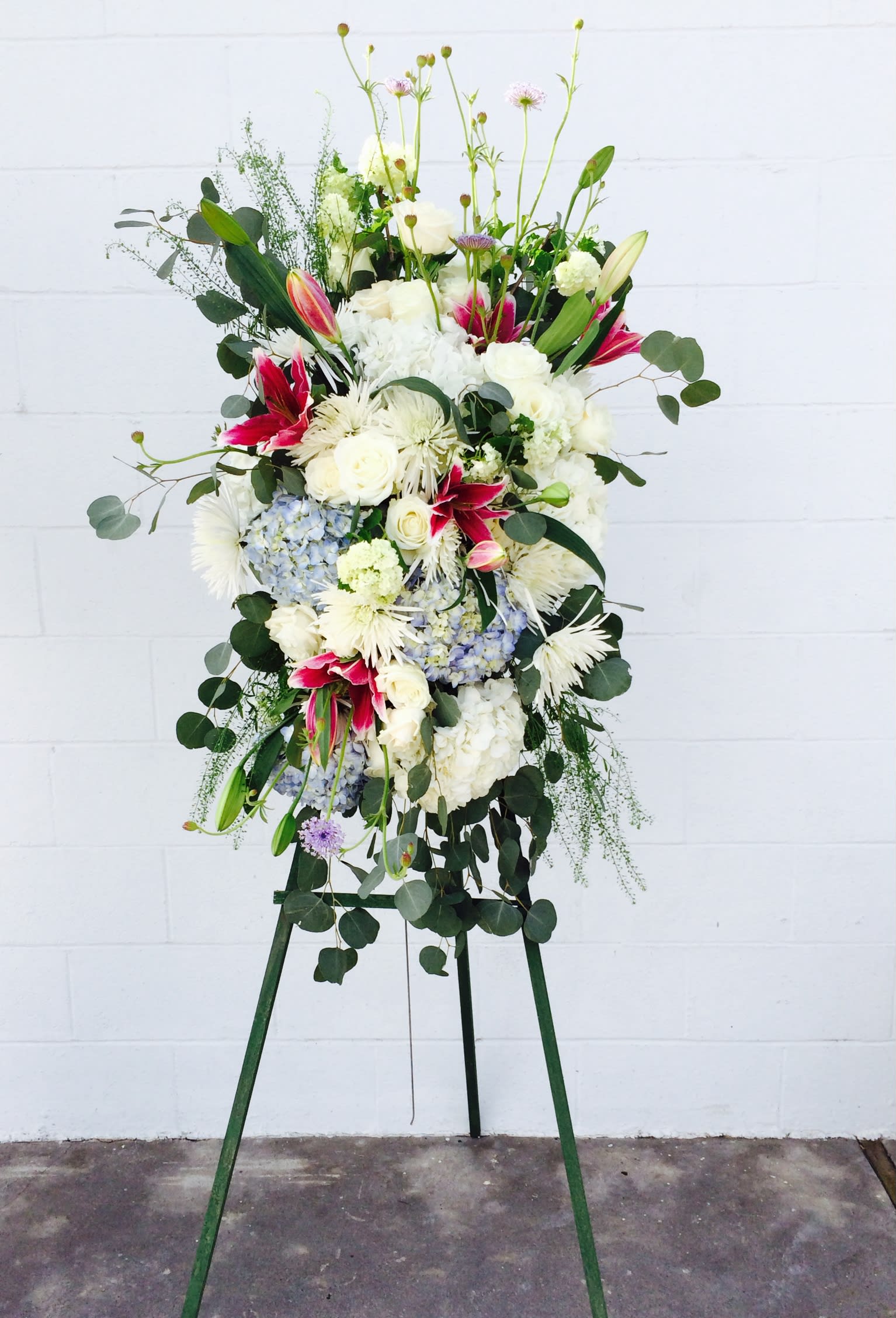 Tall floral standing arrangement with white, pink, and blue blooms on an easel