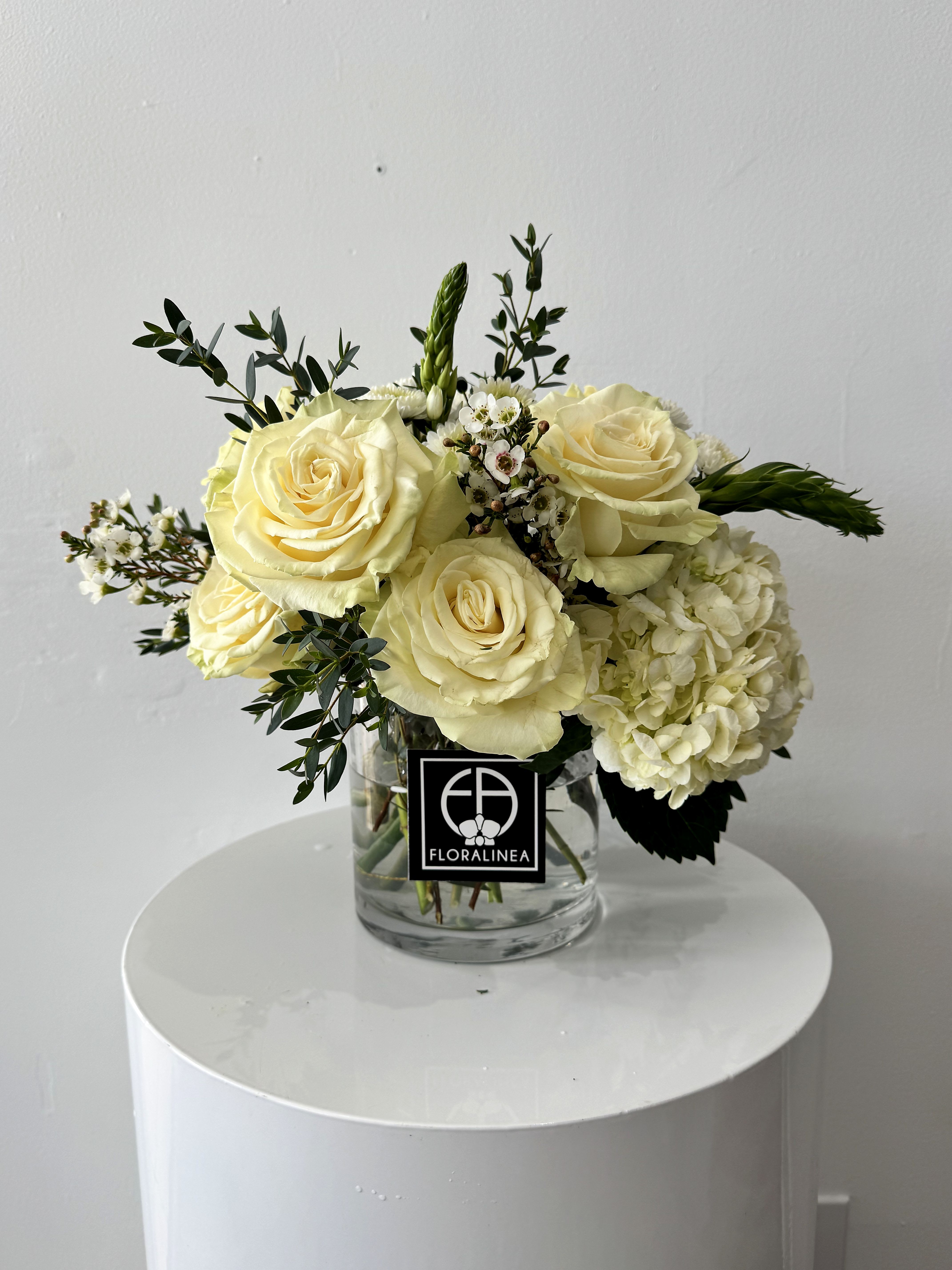 Cream rose bouquet with white hydrangea in a clear glass vase