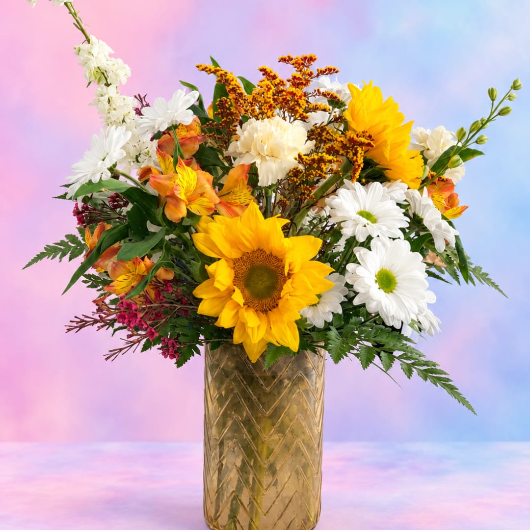 Bouquet of sunflowers, white daisies, and orange flowers in a gold vase