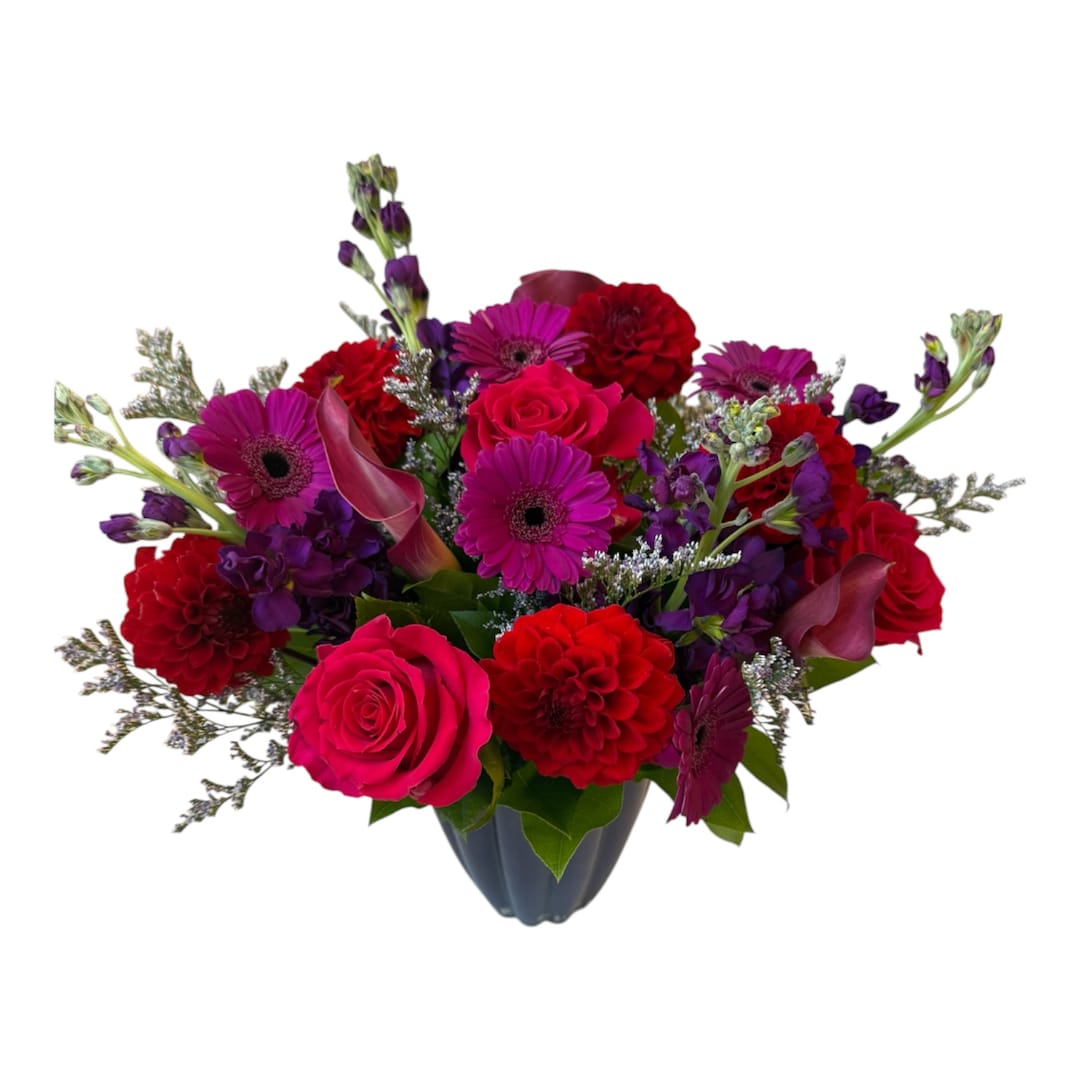 Mixed bouquet of pink, red, and purple flowers in a dark vase