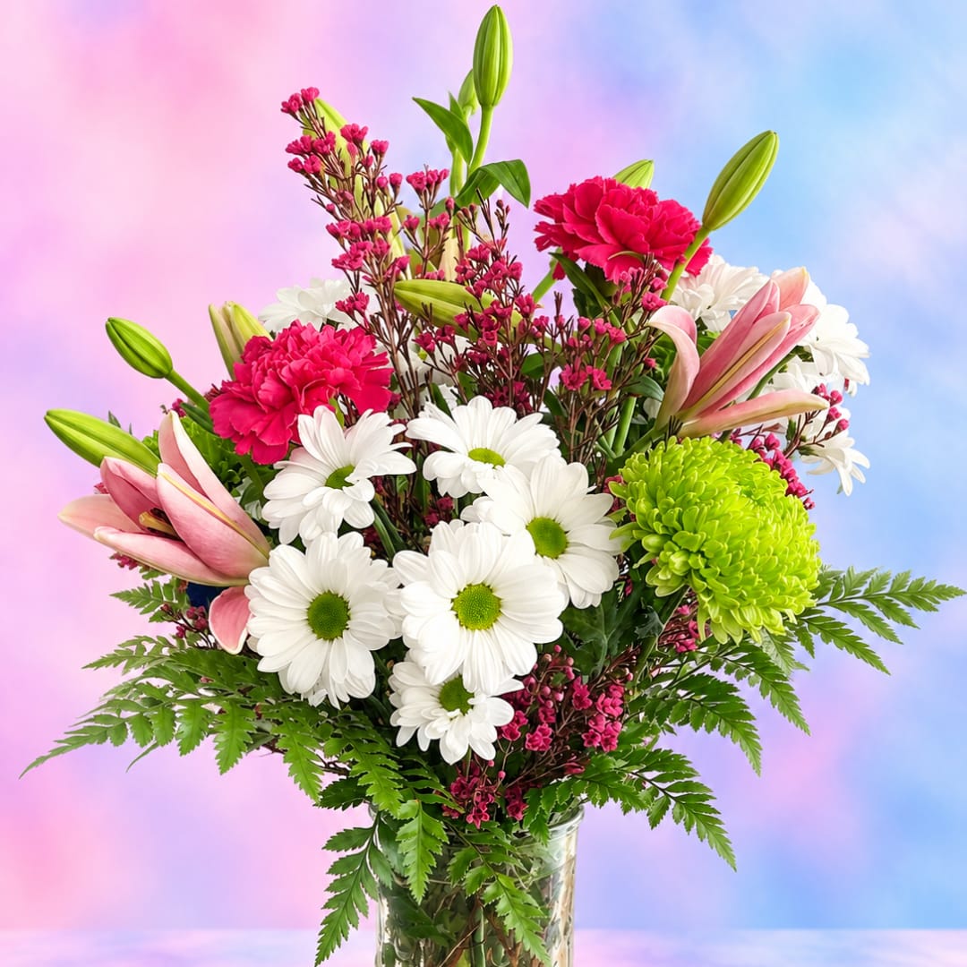 Mixed bouquet with white daisies, pink lilies, and bright carnations in a glass vase