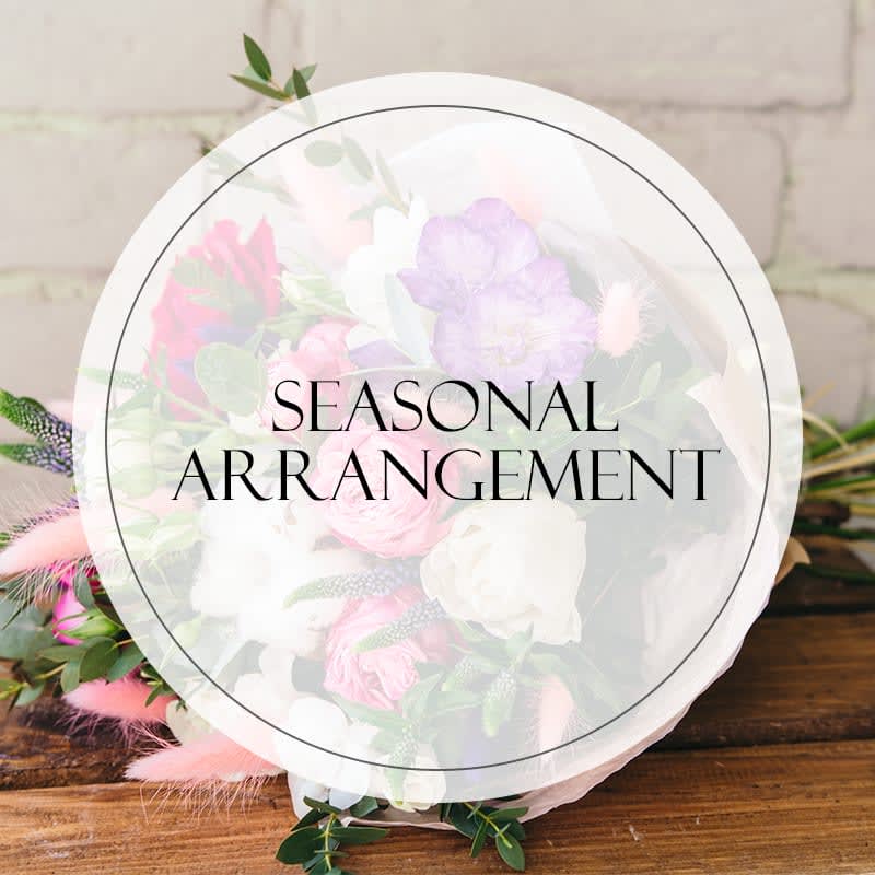 Round bouquet with pink, white, and lavender flowers wrapped in clear paper