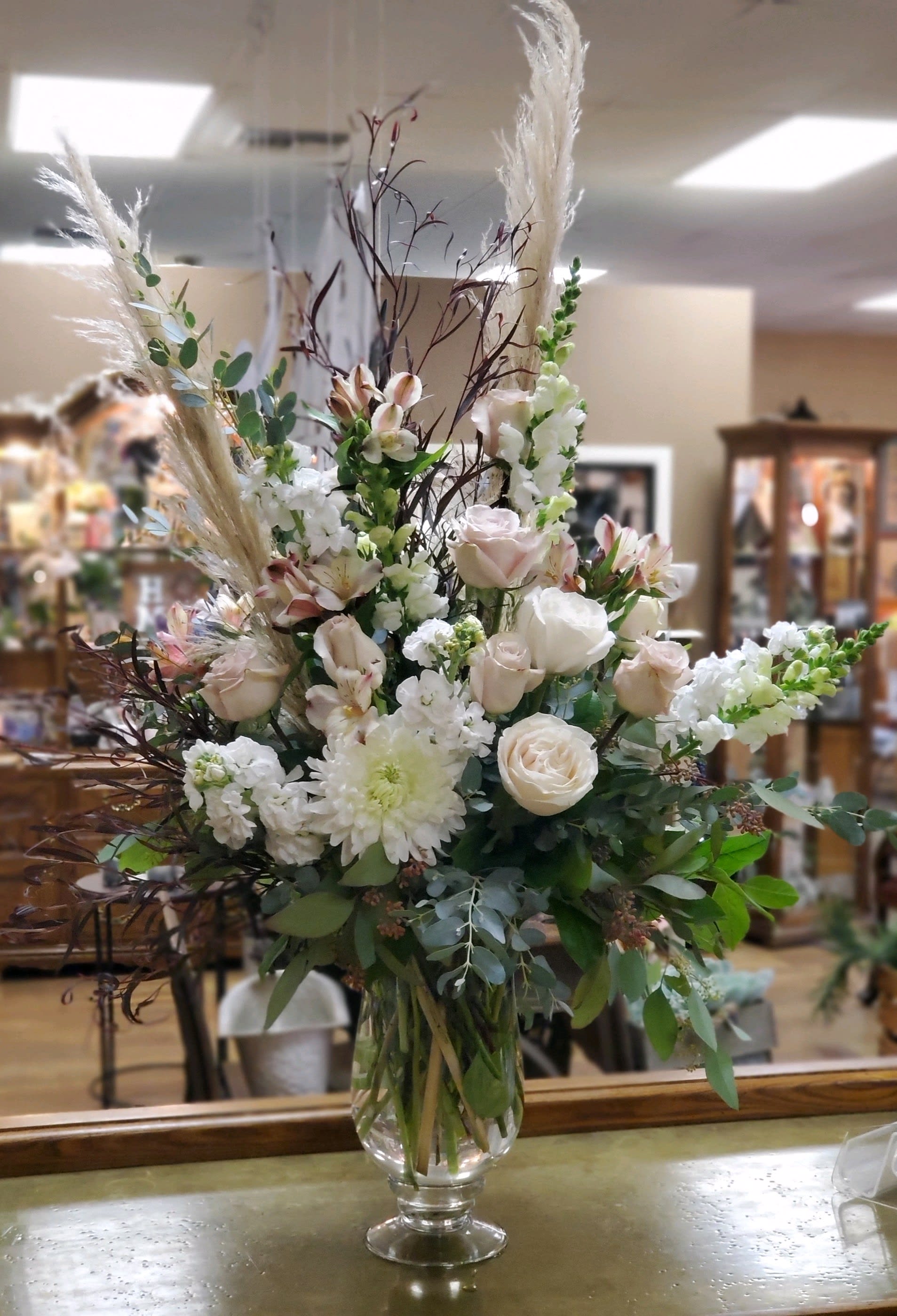 Tall bouquet of white and blush flowers in a clear glass vase