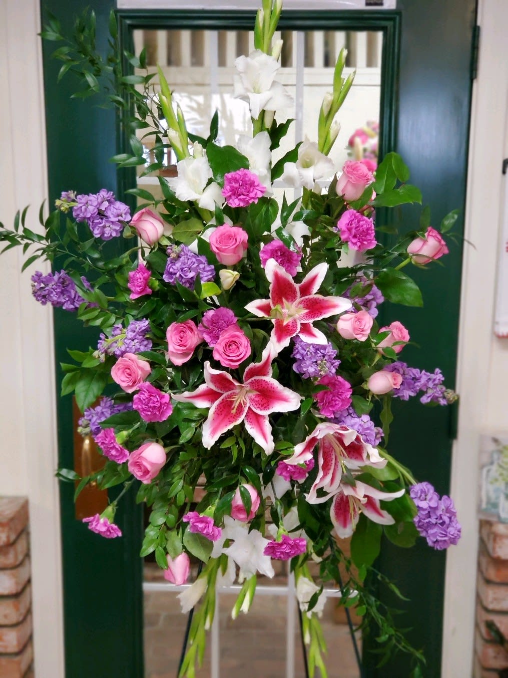 Tall floral spray with pink roses, white lilies, and purple blooms
