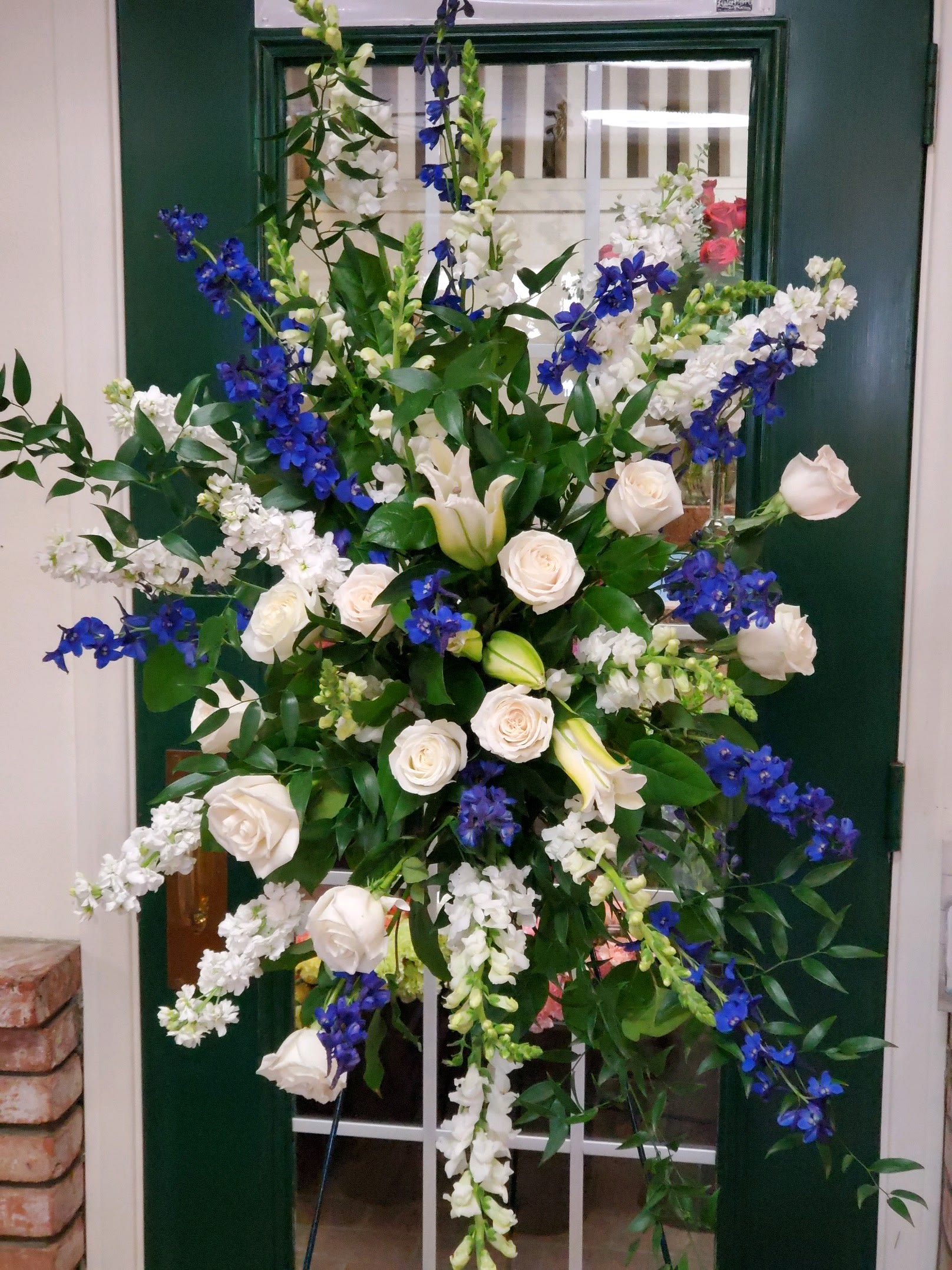 Tall floral spray with white roses, lilies, and blue flowers