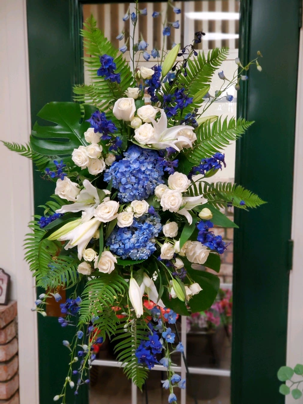 Tall blue and white floral arrangement with lilies, roses, and hydrangeas